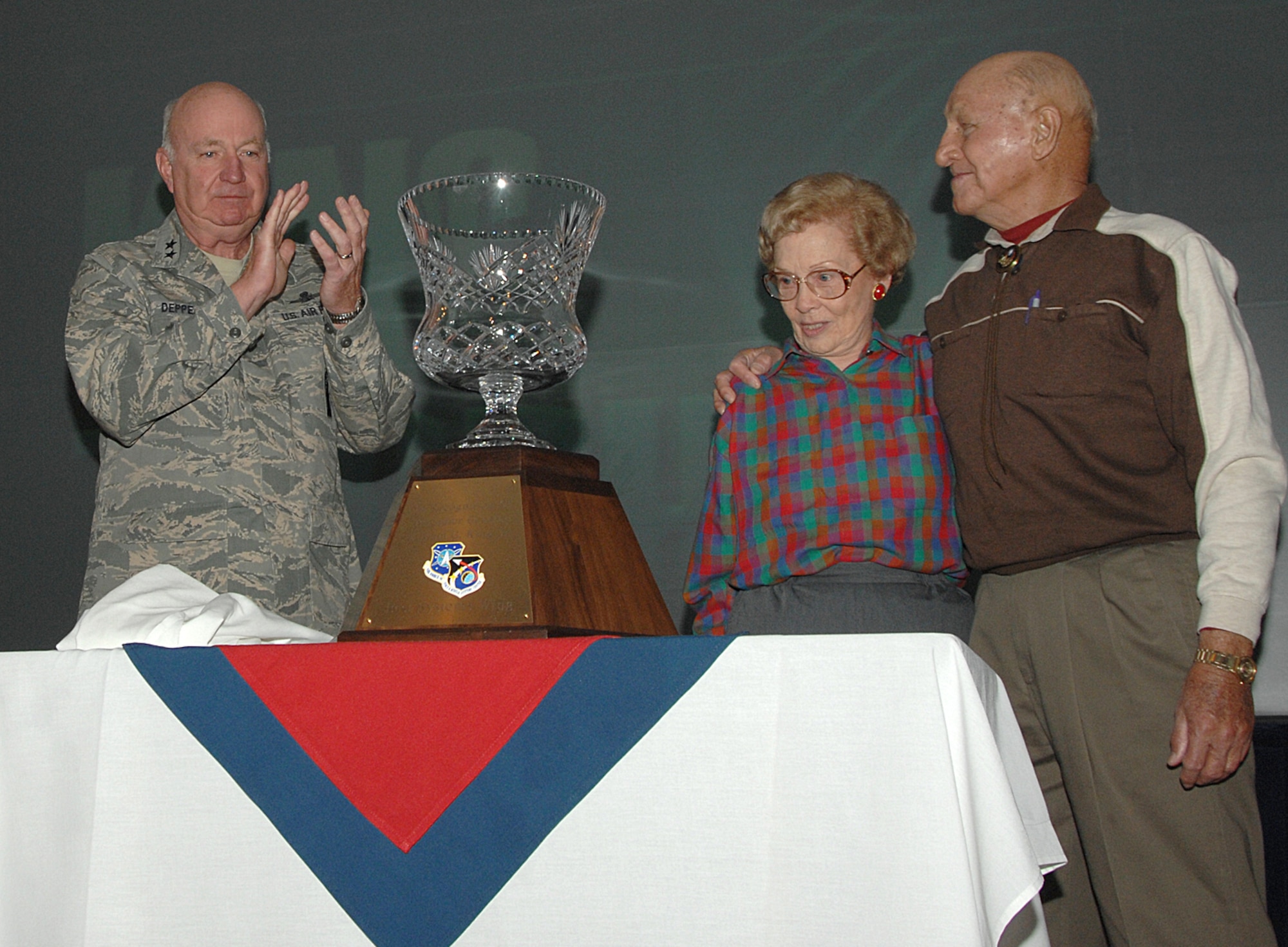 Maj. Gen. Thomas F. Deppe, Air Force Space Command vice commander, applauds at the unveiling of the Brig. Gen. William G. King Jr. trophy as General King and his wife Mary look on.  The trophy was unveiled for the first time during the opening ceremony May 8 for Guardian Challenge 2008, AFSPC's space warfighter competition.  The new trophy will go to the command's best systems wing. (U.S. Air Force photo/Tech. Sgt. Matthew Lohr)