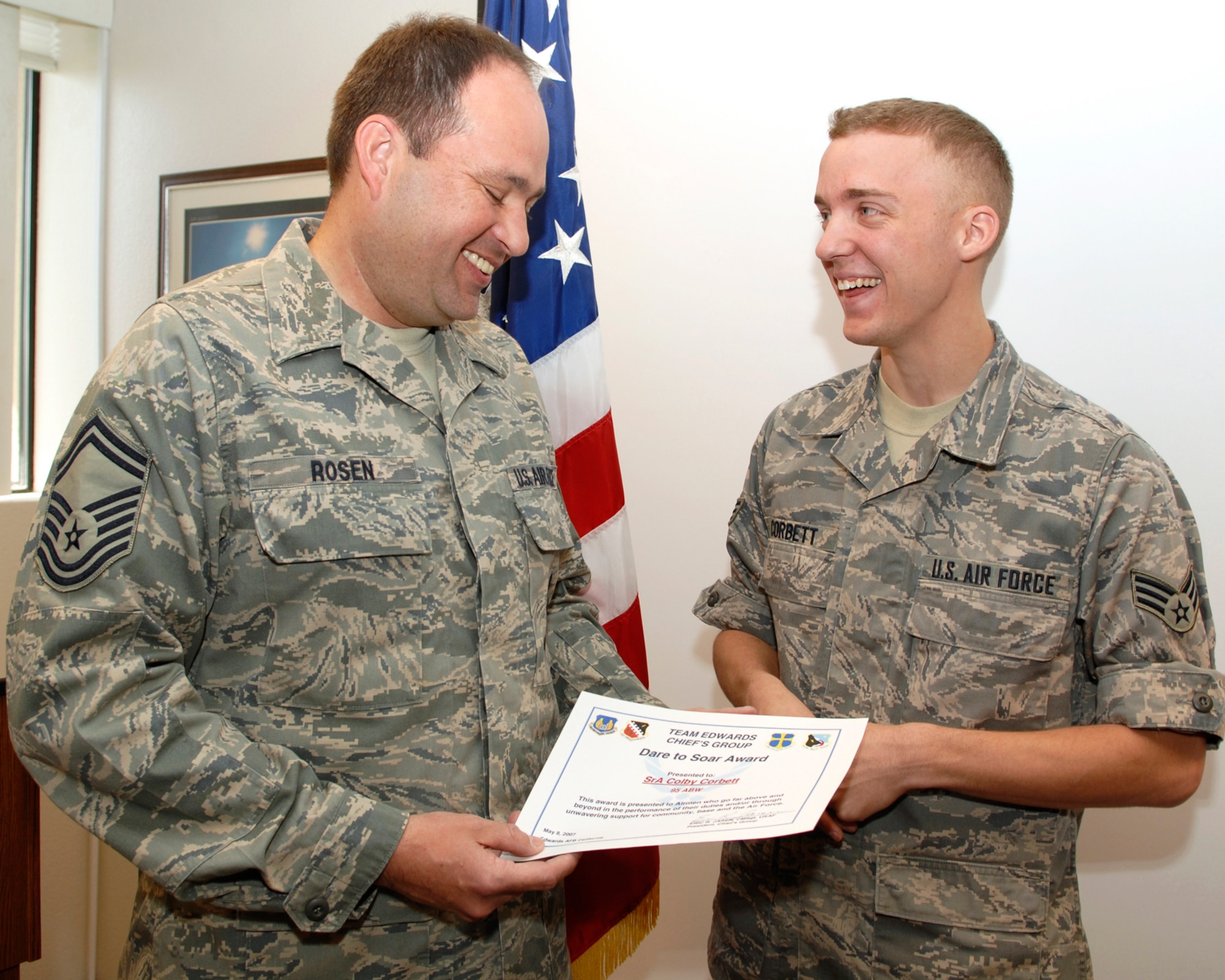 Senior Airman Colby Corbett (right), 95th Comptroller Squadron customer service representative, receives the Dare to Soar Award May 8 from Senior Master Sgt. Ben Rosen (left), Air Force Research Laboratory superintendent. Airman Corbett received the award, presented by the Chief's Group to Airman who go above and beyond in the performance of their duties, for his support of deployed servicemembers. (Air Force photo by Airman 1st Class William O'Brien)
