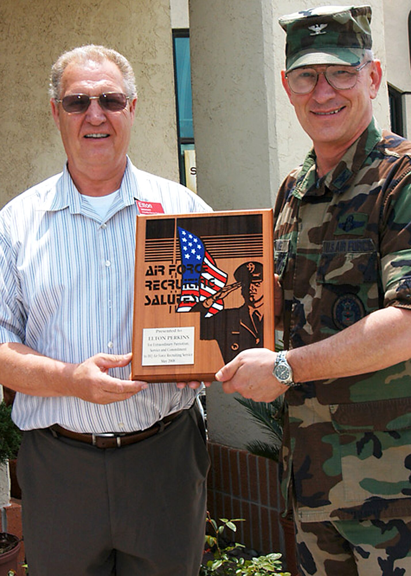 Elton Perkins accepts an Air Force Recruiting Salutes plaque from Col. Stan Chase May 7 on Randolph Air Force Base, Texas. The Air Force Recruiting Service vice commander presented the plaque in appreciation for the BXtra manager’s donation of $1,000 of Army and Air Force Exchange Service gift cards and gifts for AFRS-assigned troops in need during the winter holidays. (U.S. Air Force photo/Chet DelSignore)