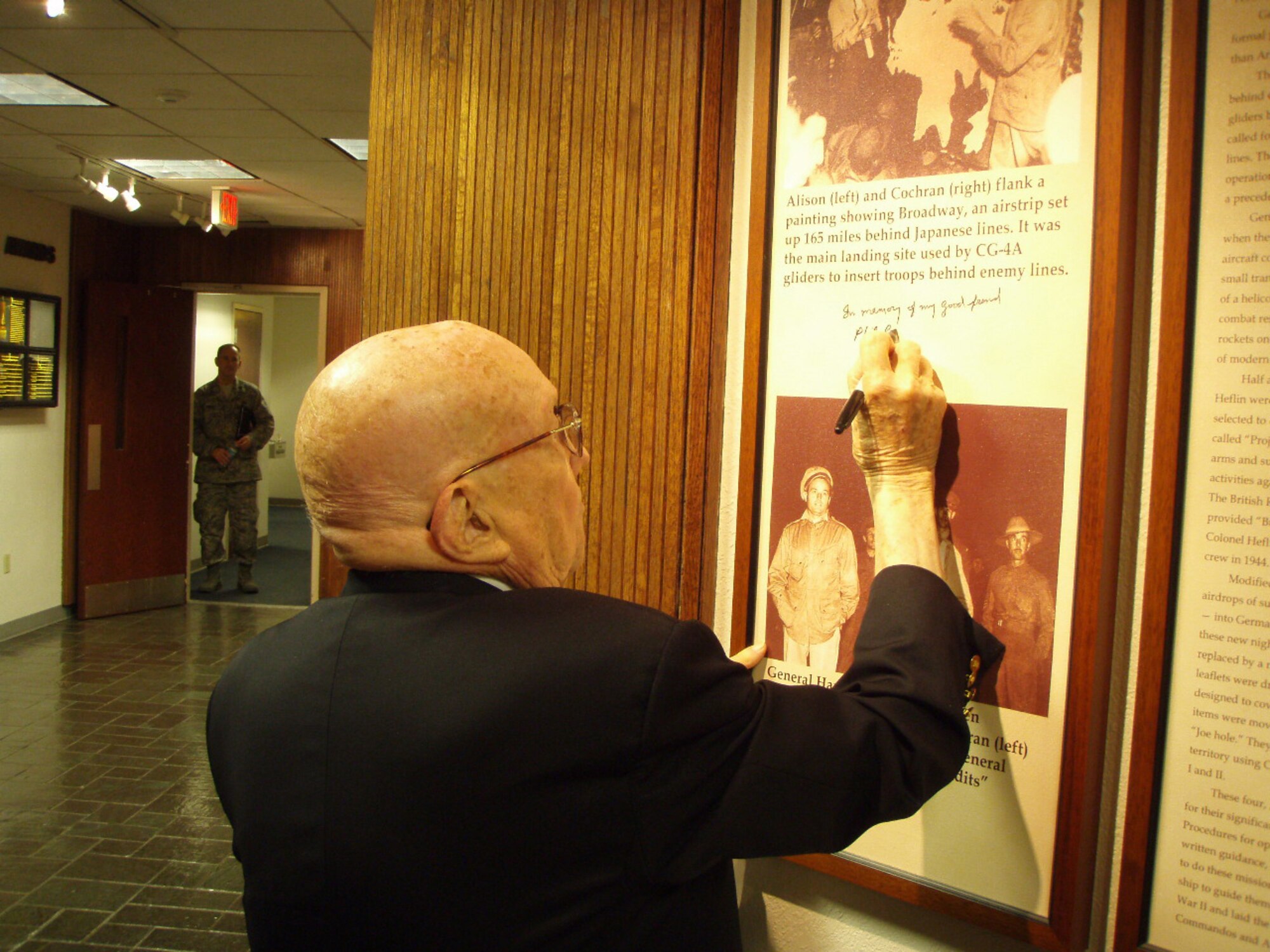 Retired Air Force Maj. Gen. John Alison signs a photo displayed in the Air Force Special Operations Command headquarters building, dedicating the photo "in memory of my good friend, Phil Cochran." The 96-year-old general is recognized as the first Air Commando, who, at the personal request of Gen. Henry "Hap" Arnold, helped Col. Cochran plan and execute Operation Thursday, a mission during which the Air Commandos alongside the British "Chindits" penetrated deep behind Japanese lines and conducted the first nighttime airfield seizure. (U.S. Air Force photo/Lt. Gen. Donald Wurster)