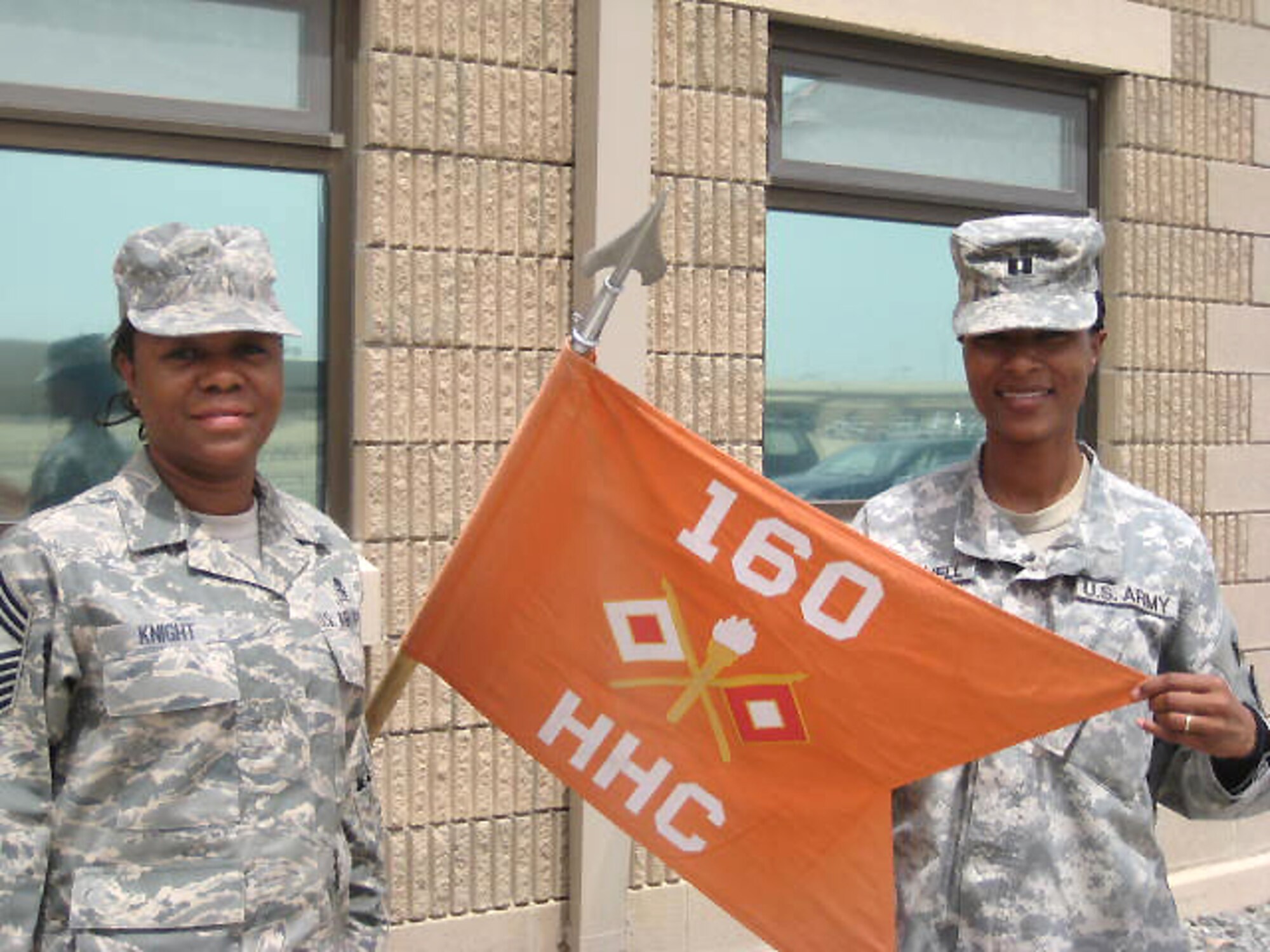 SOUTHWEST ASIA -- Chief Master Sgt. Sadie Knight stands next to the 160th Signal Brigade guideon with her daughter, Army Capt. Stacy Mitchell, at an Army camp in the Persian Gulf Region April 10, 2008.  Chief Knight and Captain Mitchell were assigned to different locations in the region, but were able to meet four times during their time in the area of operation while supporting the Global War on Terror. (U.S. Army courtesy photo)