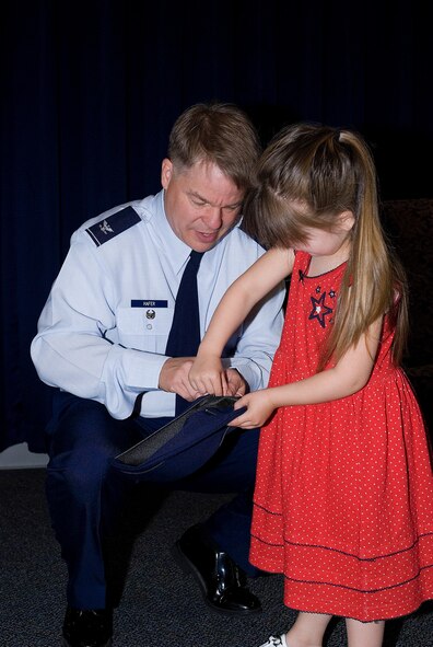 Lillian Hafer, Colonel Hafer’s granddaughter, helped put a ‘chicken’ (as she called it) on the flight cap. During Lt. Col. David Hafer’s promotion, family members helped the colonel pin on his ranks. (U.S. Air Force photo/Roland Balik)