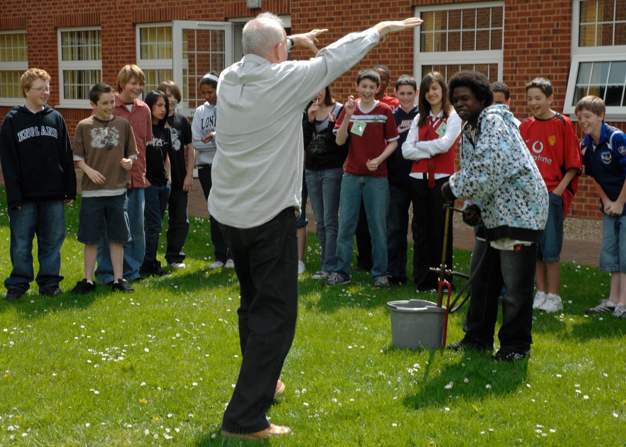 John Barwell from the Thetford Museum brought artifacts and demonstrates a stirrup pump from the World War II era with Treyvon Bradsher May 2 on RAF Feltwell.  More than 100 residents of the local community participated in the event to educate children on U.K. customs, history and heritage and to foster a relationship with the host nation. (U.S. Air Force photo by Airman 1st Class John Easterling)