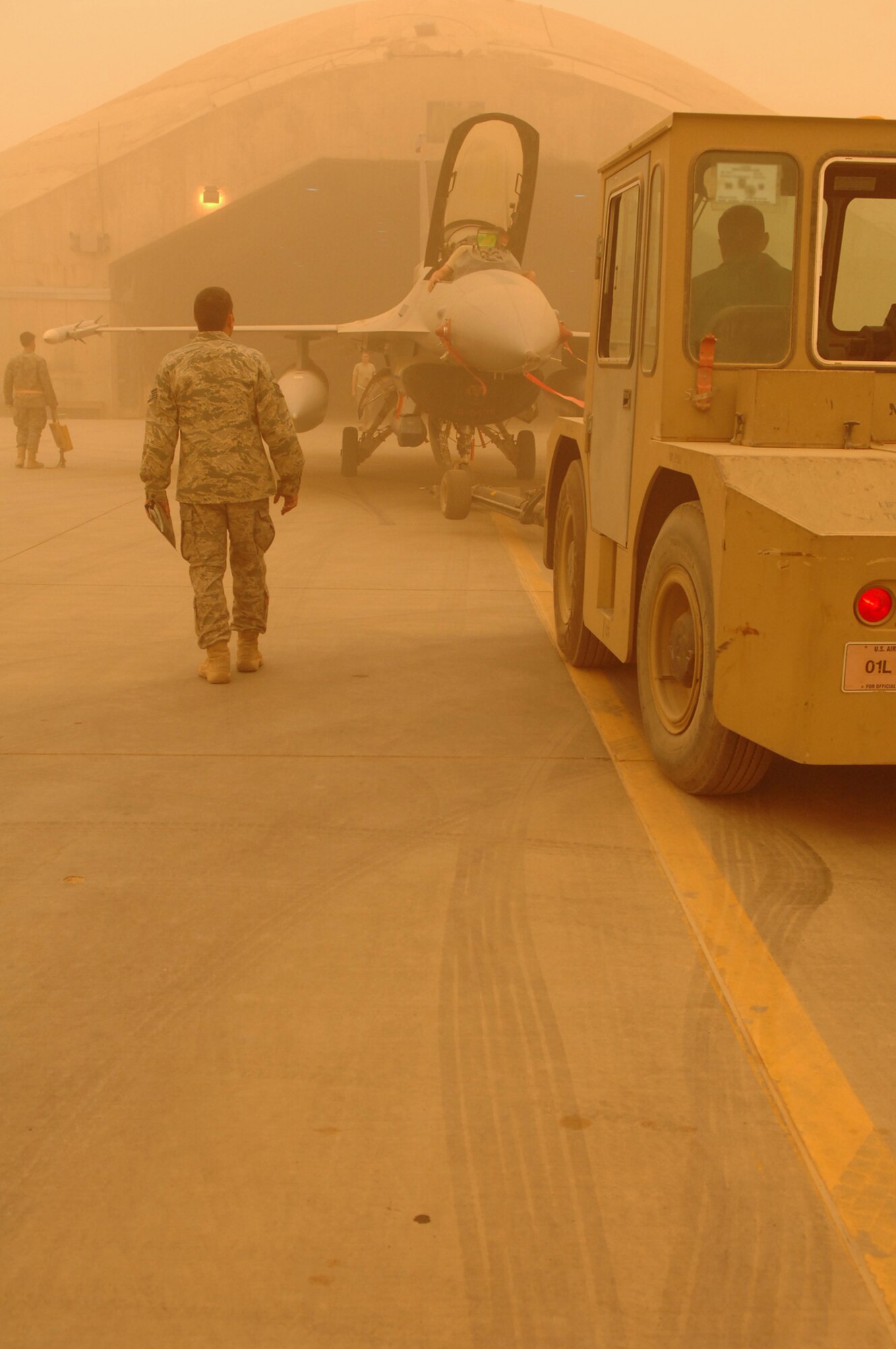 BALAD AIR BASE, Iraq -- Crew chiefs assigned to the 332nd Expeditionary Aircraft Maintenance Squadron push an F-16 Fighting Falcon into a hardened aircraft shelter during a major dust storm here, May 9. It takes a team of six crew chiefs to spot the aircraft 360 degrees around it to ensure obstacles are avoided. (U.S. Air Force photo/ Senior Airman Julianne Showalter) 