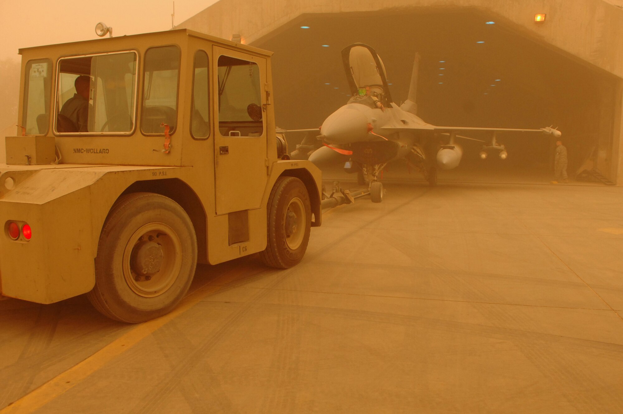 BALAD AIR BASE, Iraq -- Crew chiefs assigned to the 332nd Expeditionary Aircraft Maintenance Squadron push an F-16 Fighting Falcon into a hardened aircraft shelter during a major dust storm here, May 9. The aircraft is pushed by a tow bar that is attached to the fore main landing gear. (U.S. Air Force photo/ Senior Airman Julianne Showalter) 