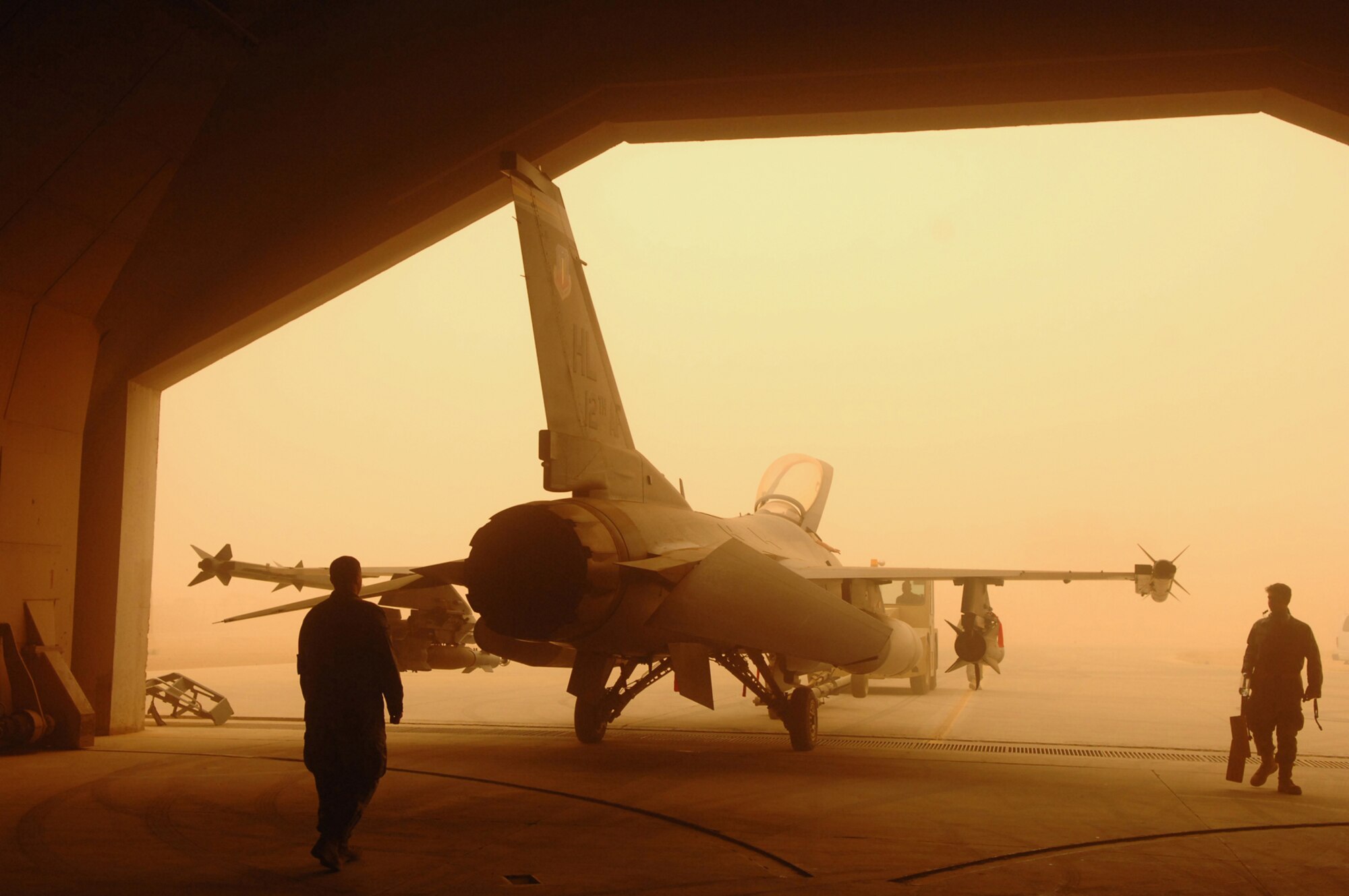 BALAD AIR BASE, Iraq -- Crew chiefs assigned to the 332nd Expeditionary Aircraft Maintenance Squadron spot an F-16 Fighting Falcon while being pushed into a hardened aircraft shelter during a major dust storm here, May 9. Protecting flightline assets from dust damage or destruction is important to maintaining the air mission. (U.S. Air Force photo/ Senior Airman Julianne Showalter) 