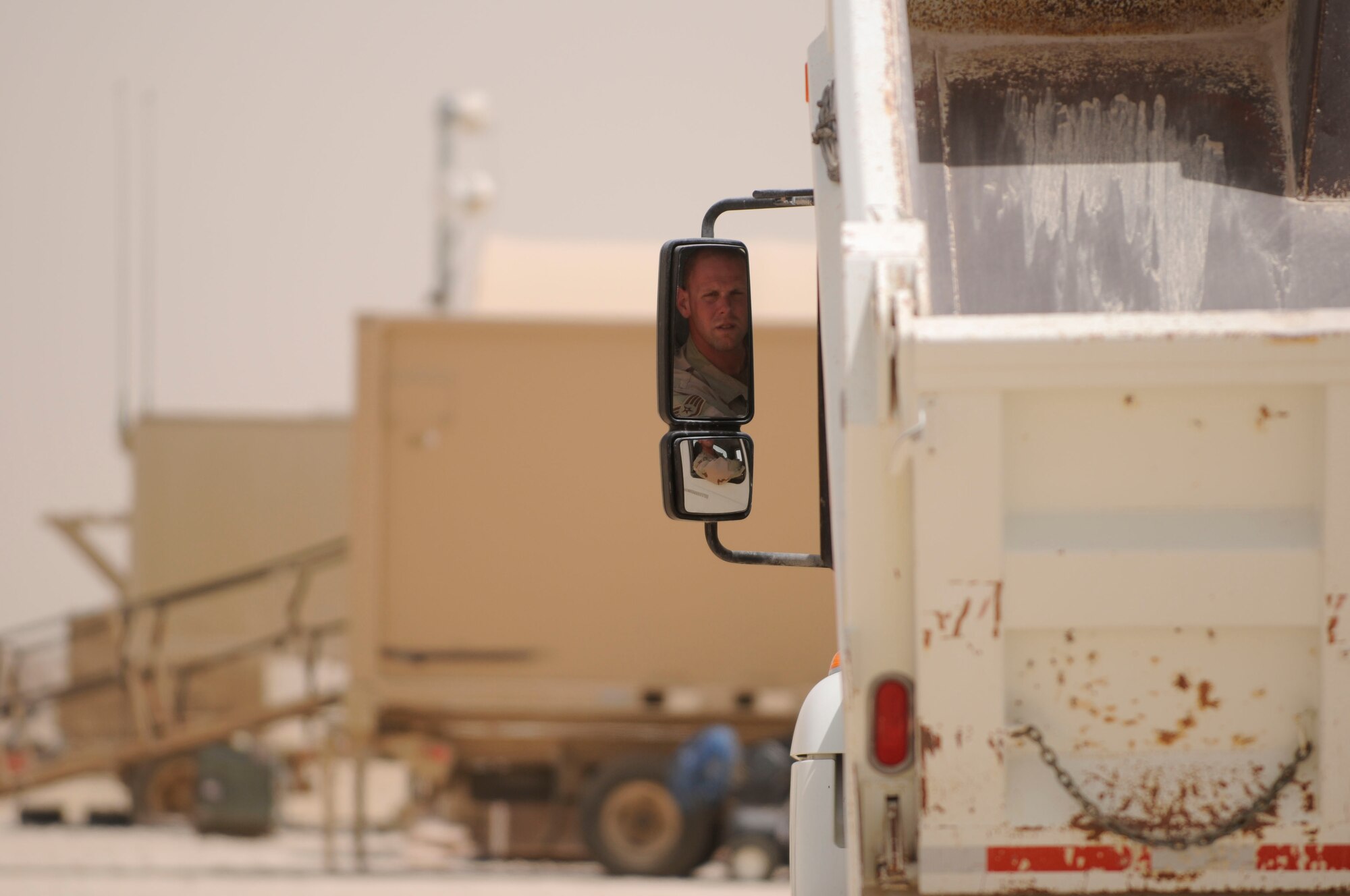 SOUTHWEST ASIA--Staff Sgt. Rosburg checks his side-view mirror before backing up his dump truck. Sergeant Rosburg led a team of five Airmen to haul more than 4,000 tons of base course fill material while constructing the new Army PATRIOT Battery site. The material was purchased from a local vendor and provides a solid base for construction. (U.S. Air Force photo/Senior Airman Domonique Simmons.)
