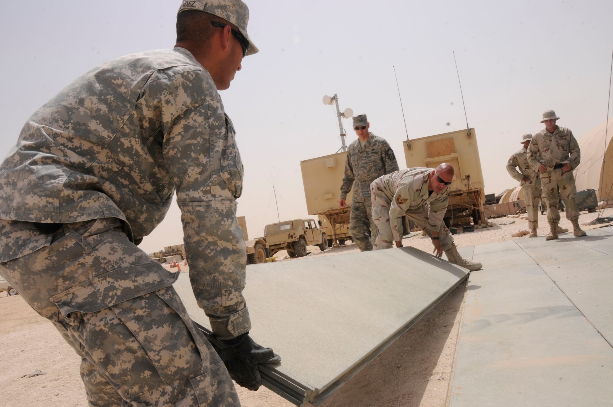 SOUTHWEST ASIA--Army Specialist Roberto Mendez (left), 2-43 Delta Battery communications specialist, holds a corner of AM2 mat while Tech. Sgt. Saul Marquez, 379th Expeditionary Civil Engineer Squadron from Travis Air Force Base, Calif., joins another to it. More than 50 Airmen and 80, 2-43rd Soldiers worked hand in hand to relocate the phased array tracking radar to intercept of target, or PATRIOT, Battery site, completed April 24. (U.S. Air Force photo by Senior Airman Domonique Simmons.)
