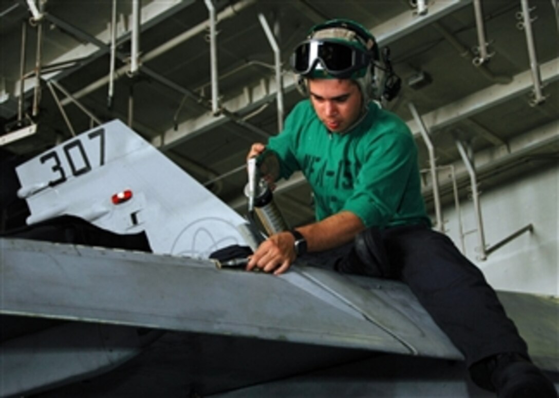 U.S. Navy Aviation Structural Mechanic Louis Velarde greases the leading edge flap transmission of an F/A-18C Hornet aboard the Nimitz-class aircraft carrier USS Abraham Lincoln (CVN 72) in the Arabian Gulf on May 7, 2008. The Lincoln is deployed to the U.S. Navy 5th Fleet area of responsibility to support Maritime Security Operations which promote stability.  
