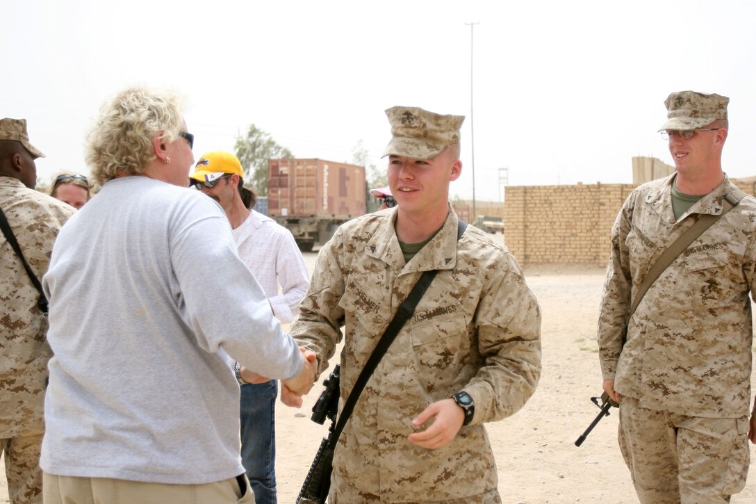 Lance Cpl. Nolan Helmer, administration clerk, S-1, Headquarters and Service Company, 2nd Battalion, 3rd Marine Regiment, Regimental Combat Team 1, shakes the hand of bassist Mark Ferry of the Saloonatics as the band visited the workspace of the Marines. The band played a 90 minute concert for the Marines to say "thank you" for the job that they are doing in Iraq.