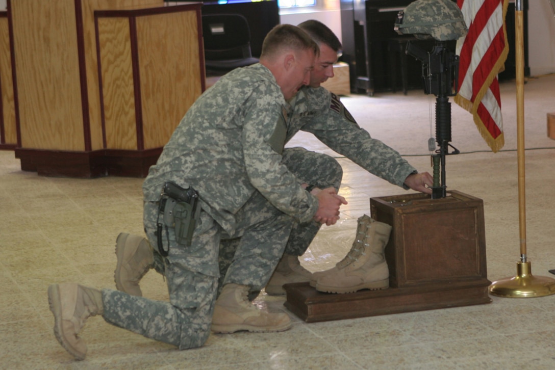 Army Capt. Chad Johnson, commanding officer, and 1st Sgt. Randy Granum,company first sergeant, both with 170th Military Police Company, 504th Military Police Battalion, which is attached to Regimental Combat Team 5, pay their respects to Army Pfc. Aaron Ward during a memorial service at the chapel on Al Asad Air Base, Iraq, Friday .  Ward, 19, a military policeman with 170th MP Co., was killed May 6 while on a combat patrol in western Anbar province, Iraq.  After the memorial service was over, service members approached the memorial to honor Ward.