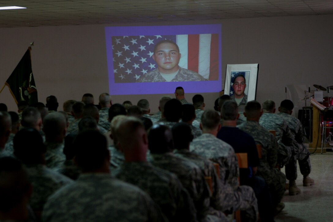 Service members watch a slide show in honor of Army Pfc. Aaron Ward during a memorial service at the chapel on Al Asad Air Base, Iraq, Friday.  Ward, 19, a military policeman with 170th Military Police Company, 504th MP Battalion, which is attached to Regimental Combat Team 5, was killed May 6 while on a combat patrol in western Anbar province, Iraq.  Ward received military honors during the service, which included a 21-gun salute.::r::::n::
