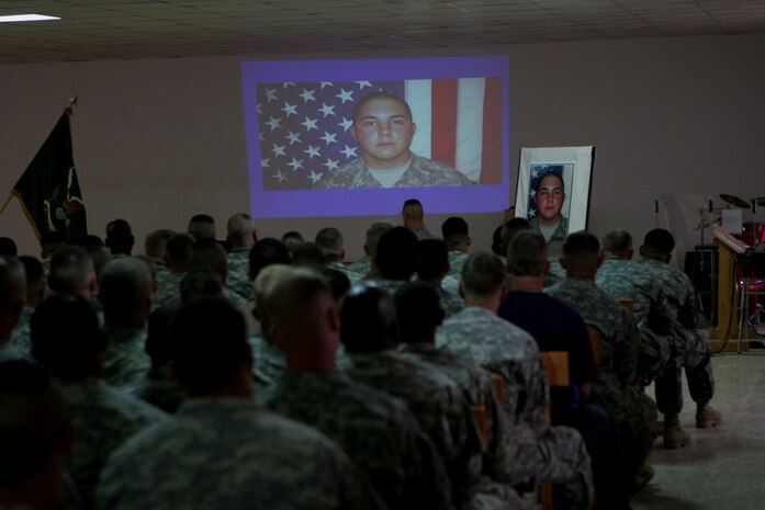 Service members watch a slide show in honor of Army Pfc. Aaron Ward during a memorial service at the chapel on Al Asad Air Base, Iraq, Friday.  Ward, 19, a military policeman with 170th Military Police Company, 504th MP Battalion, which is attached to Regimental Combat Team 5, was killed May 6 while on a combat patrol in western Anbar province, Iraq.  Ward received military honors during the service, which included a 21-gun salute.::r::::n::