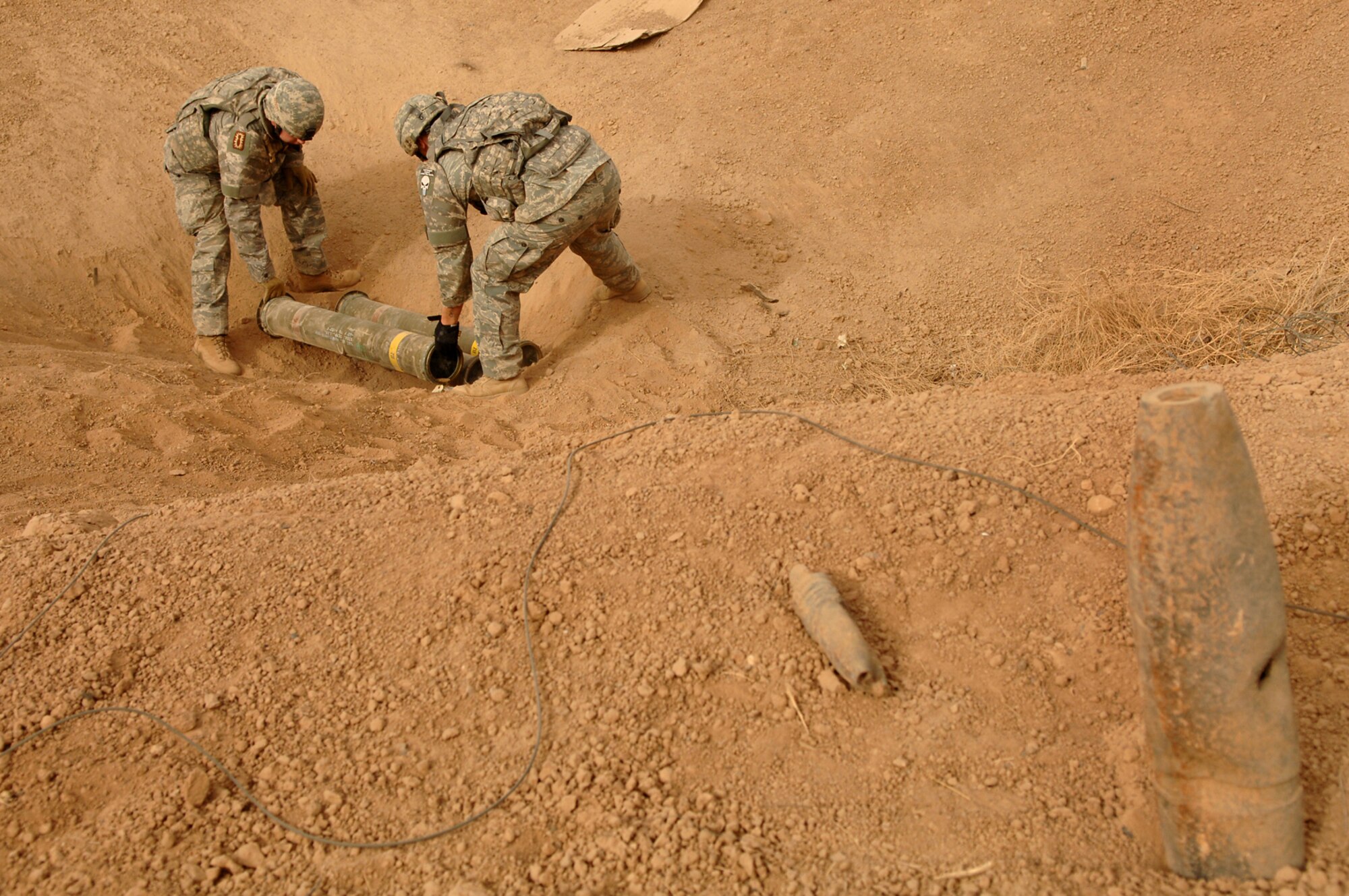 BALAD AIR BASE, Iraq -- Staff Sgts. Andrew Filcher and Christopher Ferrell, 332nd Expeditionary Civil Engineer Squadron explosive ordnance disposal team members, place three 40-pound unserviceable guided missiles in a crater before disposal here, May 9. Controlled detonations are a means of disposing of unexploded ordnances to ensure they don?t fall into possession of enemy forces. Sergeant Filcher is deployed from Hill Air Force Base, Utah; Sergeant Ferrell is deployed from Charleston Air Force Base, S.C. (U.S. Air Force photo/ Senior Airman Julianne Showalter) 