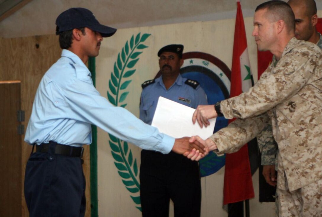 Capt. Gerard C. Dempster, Headquarters and Service Company Commander and the battalion's direct liaison for the Iraqi Security Forces, 1st Battalion, 9th Marine Regiment, Regimental Combat Team 1, shakes hands with an Iraqi Policemen during a graduation ceremony at Al Anbar Ramadi District Training Headquarters May 8. Upon graduating from the training, the policemen go to their precinct and officially begin working as an Iraqi Policemen. "The policemen will go to a variety of different stations within all of the Ramadi precincts almost immediately after they graduate or as soon as their station directs them to report," said Capt. Gerard C. Dempster, Headquarters and Service Company Commander with 1st Battalion, 9th Marine Regiment, Regimental Combat Team 1 and direct liaison to the Iraqi Security Forces.