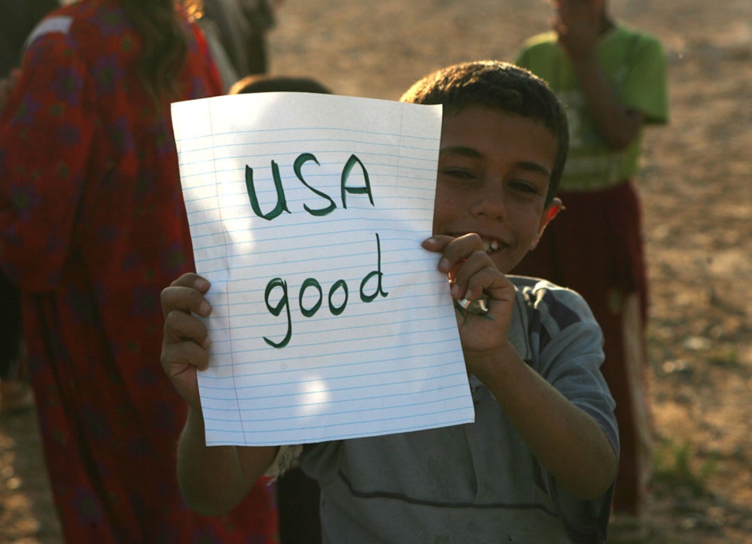 An Iraqi boy happily holds up a sign near Baghdadi, Iraq, Saturday which an older Iraqi boy wrote in English for him on paper that was donated by the Freemont County School District Number One in Wyoming. Select Marines with Headquarters Company, Regimental Combat Team 5 are conducting operations at Combat Outpost Timberwolf as a provisional rifle platoon. The PRP is made up of non-infantry Marines trained to do a basic rifleman's job. Routinely the Marines here interact with the locals and pass out school supplies to the children to help with the locals needs.