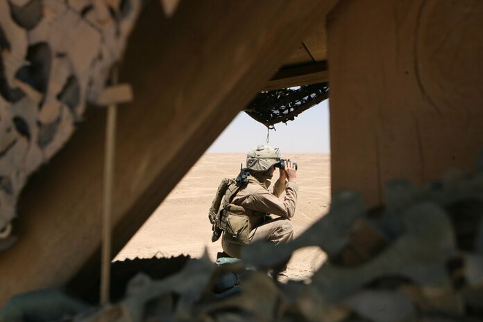 Lance Cpl. Spencer A. Johnson, 20, a data network system technician with Headquarters Company, Regimental Combat Team 5, who is from Jacksonville, N.C., looks through binoculars as he stands watch at Combat Outpost Timberwolf, Iraq, May 10. Marines and sailors with Headquarters Co. make up the provisional rifle platoon at COP Timberwolf.  The PRP routinely patrols with the Iraqi Police and aids the local community with supplies and medical attention.