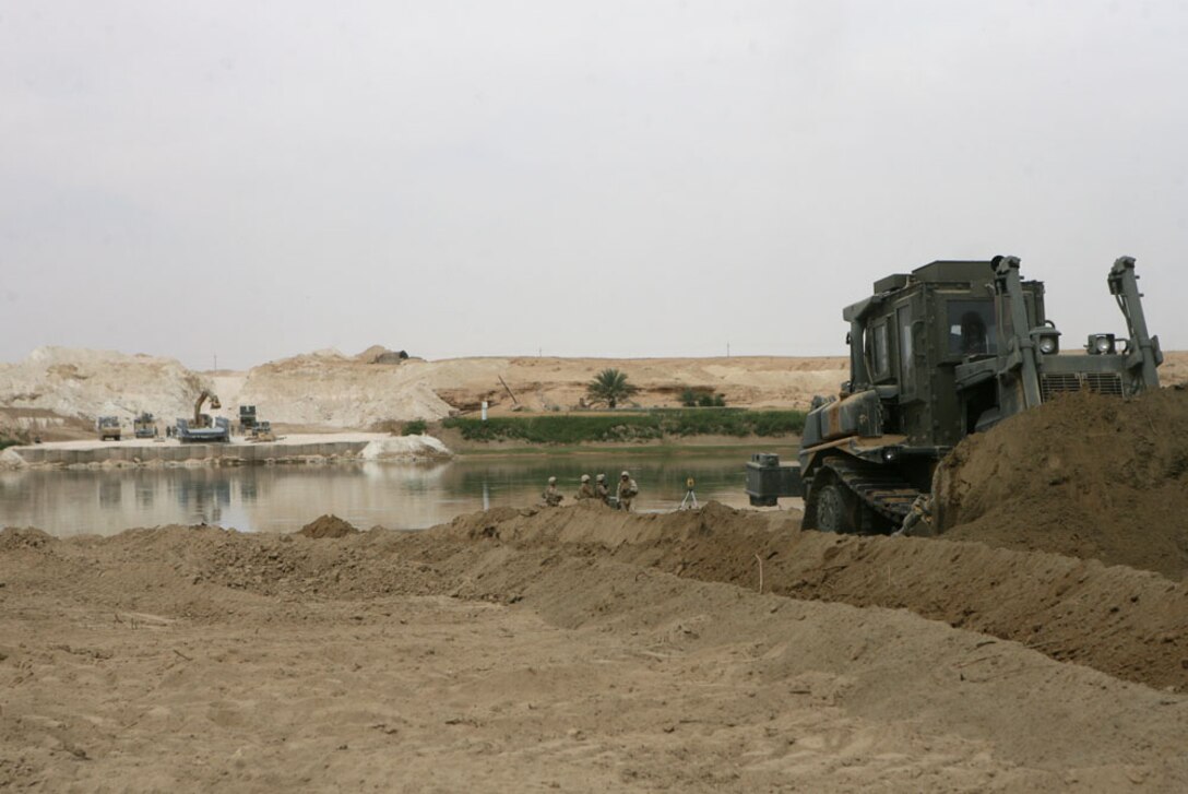 Navy Seabeas with Navy Mobile Construction Battalion 17, build a local bridge near Jubah, Iraq May, 10. The bridge will allow traffic to cross the river easier. Marines and sailors with Headquarters Company, Regimental Combat Team 5, who make up the provisional rifle platoon here, are tasked to provide site security for the sailors while they construct the bridge.
