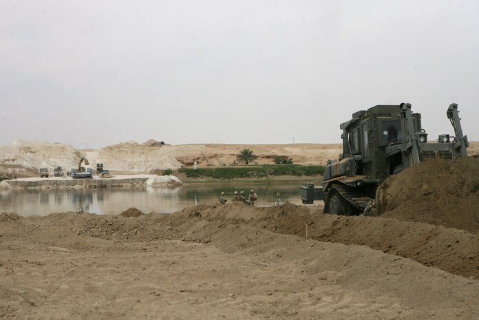 Navy Seabeas with Navy Mobile Construction Battalion 17, build a local bridge near Jubah, Iraq May, 10. The bridge will allow traffic to cross the river easier. Marines and sailors with Headquarters Company, Regimental Combat Team 5, who make up the provisional rifle platoon here, are tasked to provide site security for the sailors while they construct the bridge.