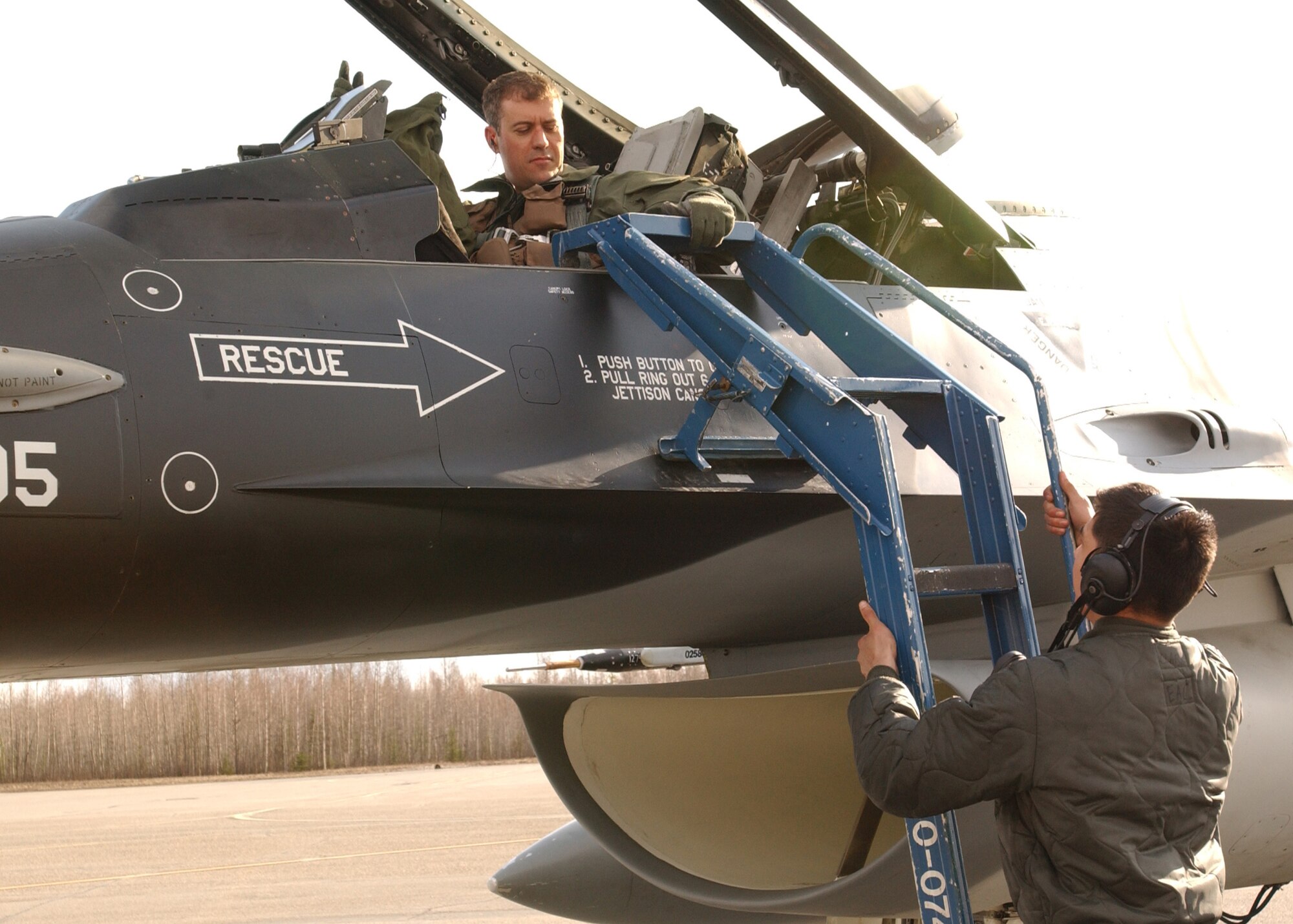 Maj. Gene Cassingham, 18th Aggressor Squadron F-16 pilot, is assisted by a member of the ground crew May 7 after the flight in which he reached his 2,000 hour mark.  He is the first 18th AGRS pilot since the activation of the 18th AGRS to reach this career hallmark. Major Cassingham is now one of five pilots on Eielson AFB with a flying time of 2,000 hours or more in the F-16, most of those pilots are lieutenant colonels or higher in rank. There are 541 total pilots in the Air Force who have reached the same milestone. (U.S. Air Force photo by Master Sgt. Jill Victor)
