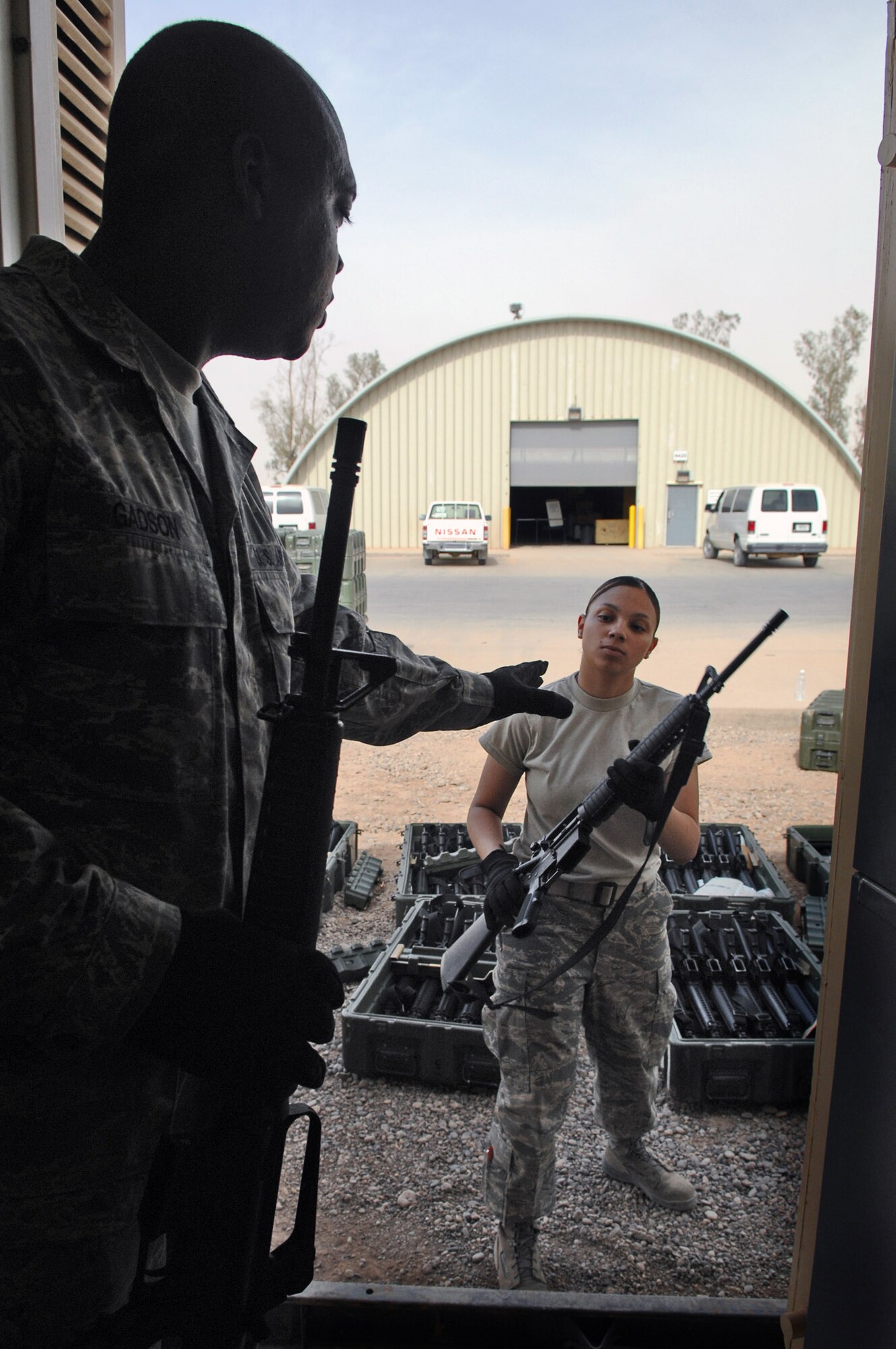 Airman 1st Class Lianette Williams hands an M-16 rifle to Tech. Sgt. Eric Michel April 5 at Balad Air Base, Iraq. Airman Williams is a 332nd Expeditionary Logistics Readiness Squadron base supply manager deployed from Luke Air Force Base, Ariz. Sergeant Michel is the 332nd ELRS base supply manager deployed from Ellsworth AFB, S.D. (U.S. Air Force photo/Senior Airman Julianne Showalter) 
