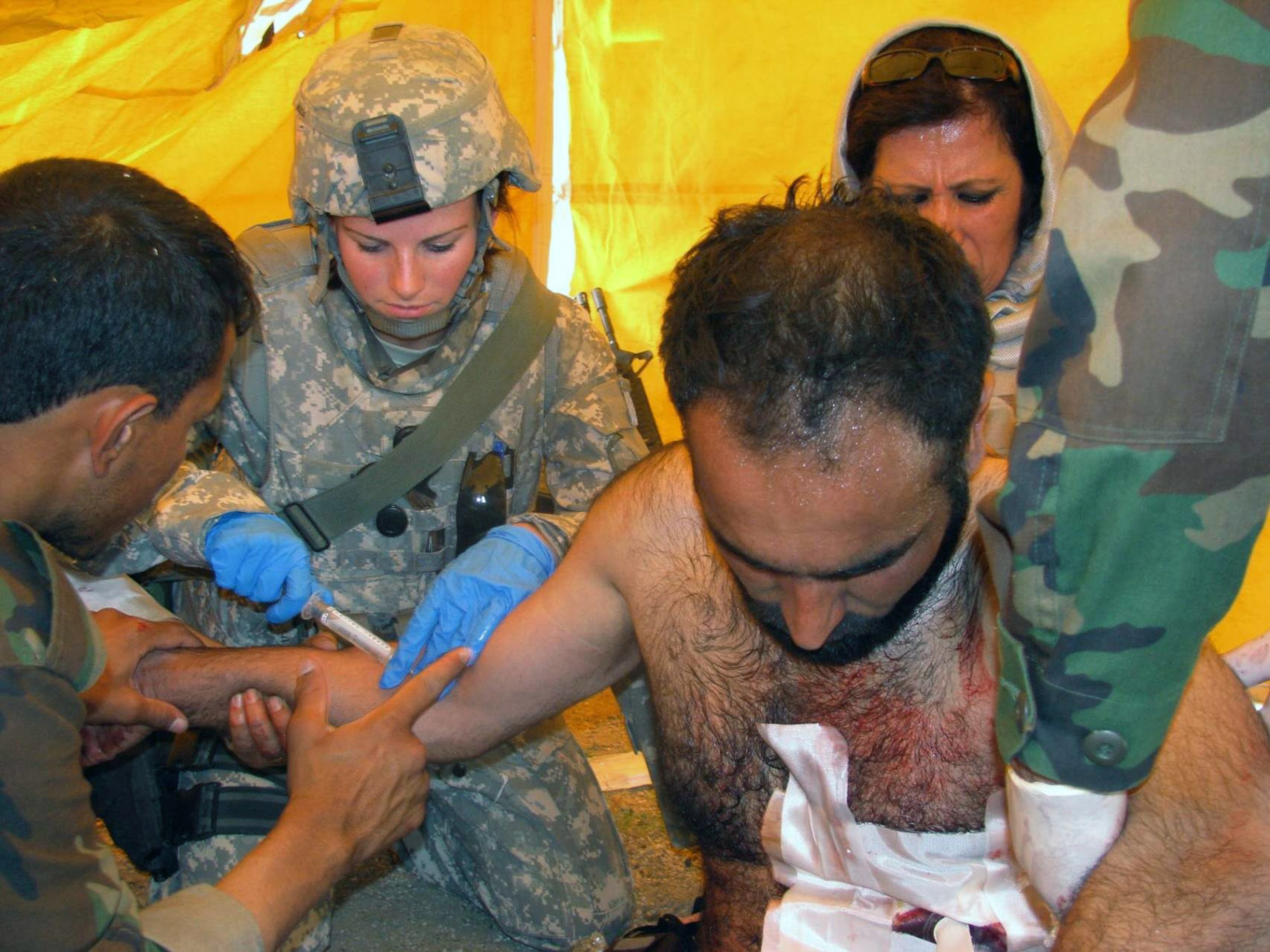 Senior Airman Robin Mock helps stabilize an Afghan national police officer with a gunshot wound May 7 in the Laghman Province in Afghanistan. Laghman Provincial Reconstruction Team medics and an Afghan national army doctor were conducting a joint-medical outreach in Sur Ghar Village at the time of the incident. The Afghan officer was wounded during an unrelated poppy eradication mission a few kilometers away. (U.S. Air Force photo) 
