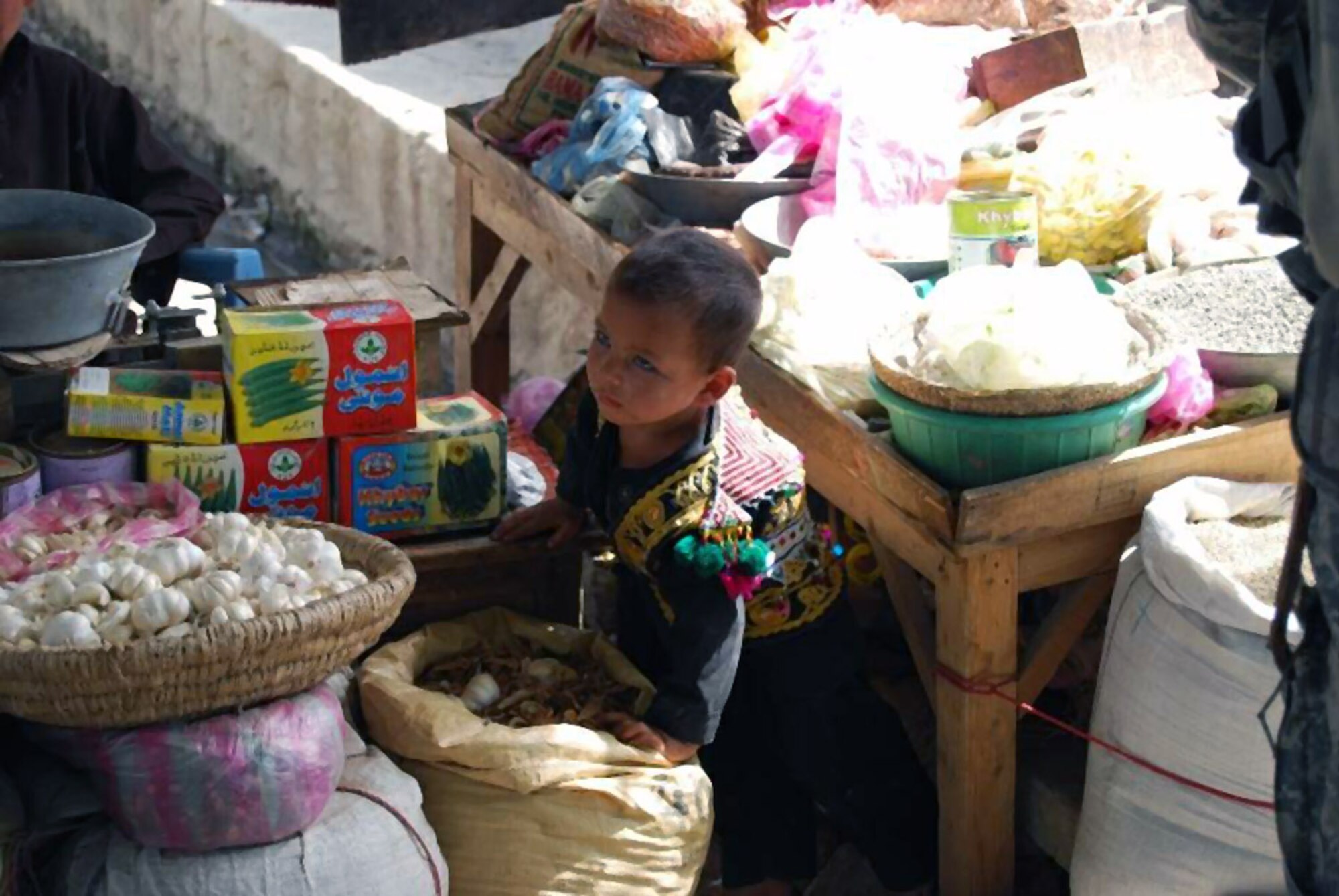 A young girl crawls from under her parents' selling table during a Provincial Reconstruction Team economic assessment of Mehtar Lam May 3 in the Laghman Province in Afghanistan. The assessment, conducted by members of Army civil affairs, confirmed that the soaring flour prices affecting Afghanistan are also affecting Laghman Province, with many reporting prices doubling and tripling before the Islamic Republic of Afghanistan took action. In April, the IRoA cabinet members put aside $2.5 billion Afghani so that the ministry of finance could buy more wheat and ease the burden on the Afghan people. (U.S. Army photo)
