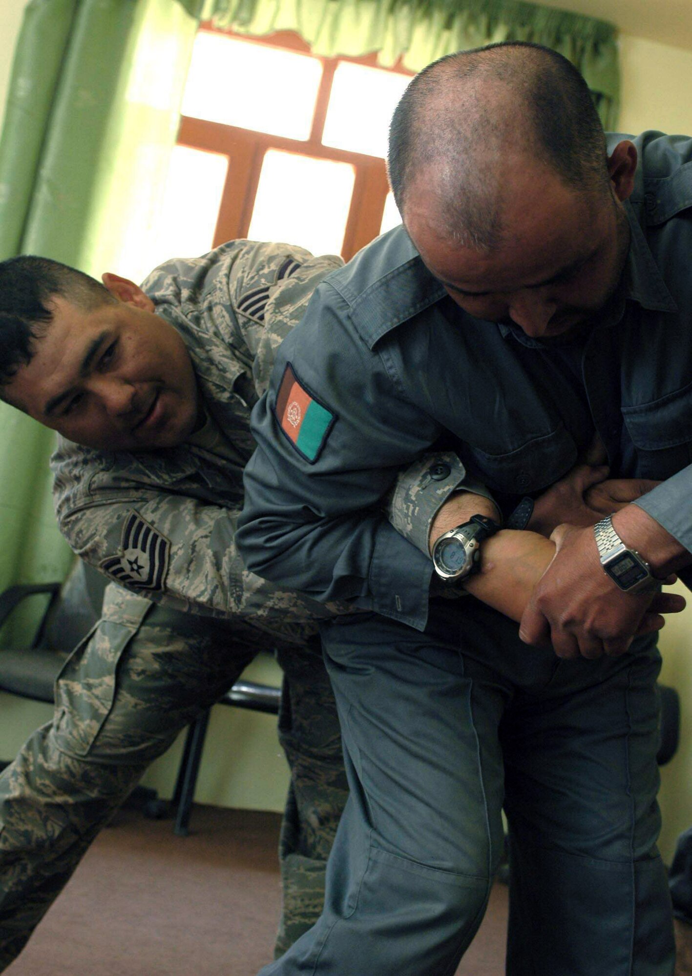 Tech. Sgt. Chris Padron demonstrates a restraint technique for a member of the Afgahnistan National Police as part of a training class held May 8 at Dandar village, in the Parwan province of Afghanistan. Access to resource control was also taught during the training. Sergeant Padron is a Provincial Reconstruction Team member deployed from Cannon Air Force Base, N.M. (U.S. Air Force photo)