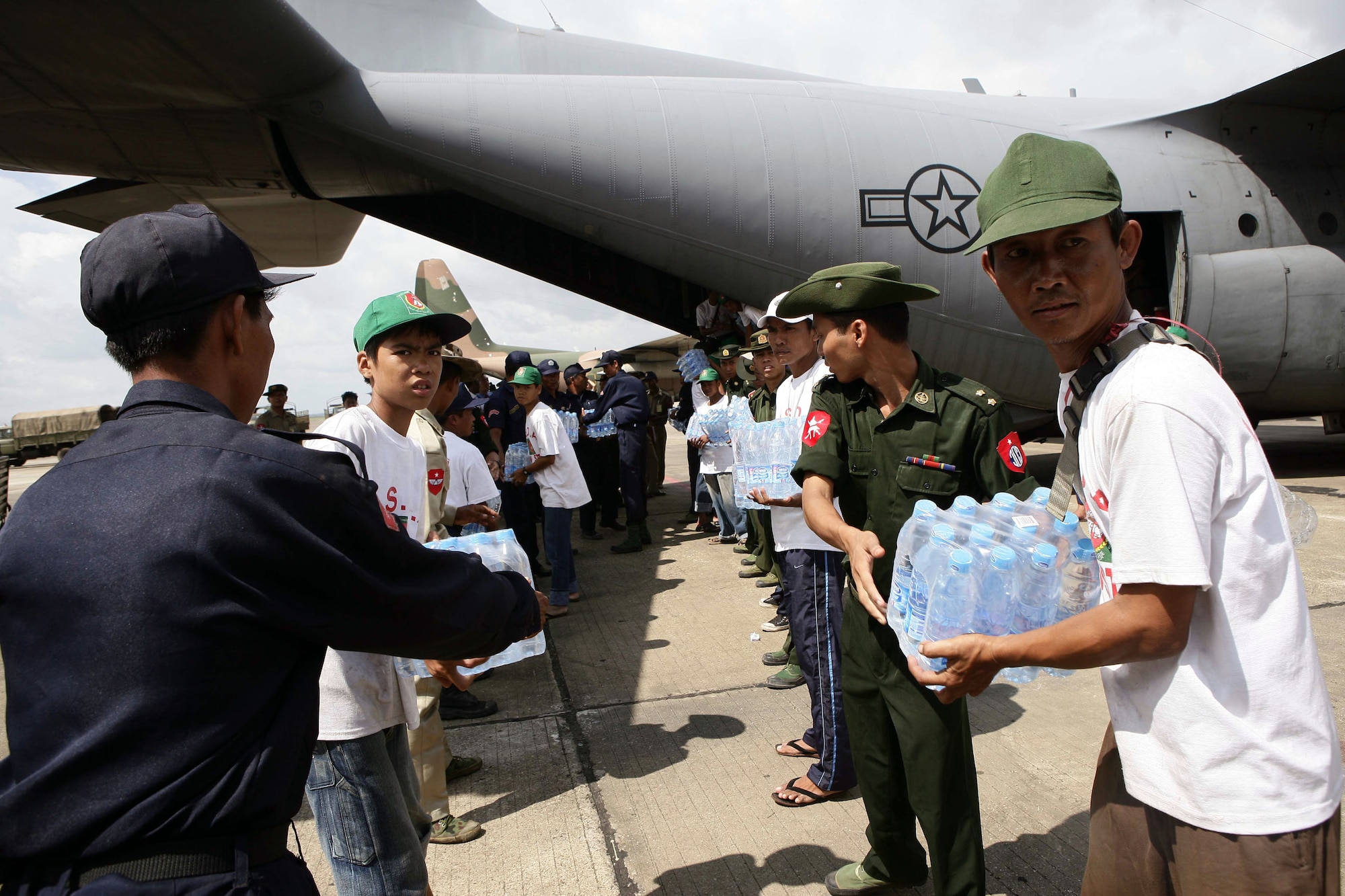 Burma servicemembers form a line to carry water supplies off a U.S. Air Force C-130 Hercules May 12 at the Yangon International Airport in Burma. The plane carrying water, food and medical supplies provided relief to Burma, which was struck by Cyclone Nargis May 2. (U.S. Marine Corps photo/Sgt. Andres Alcaraz) 
