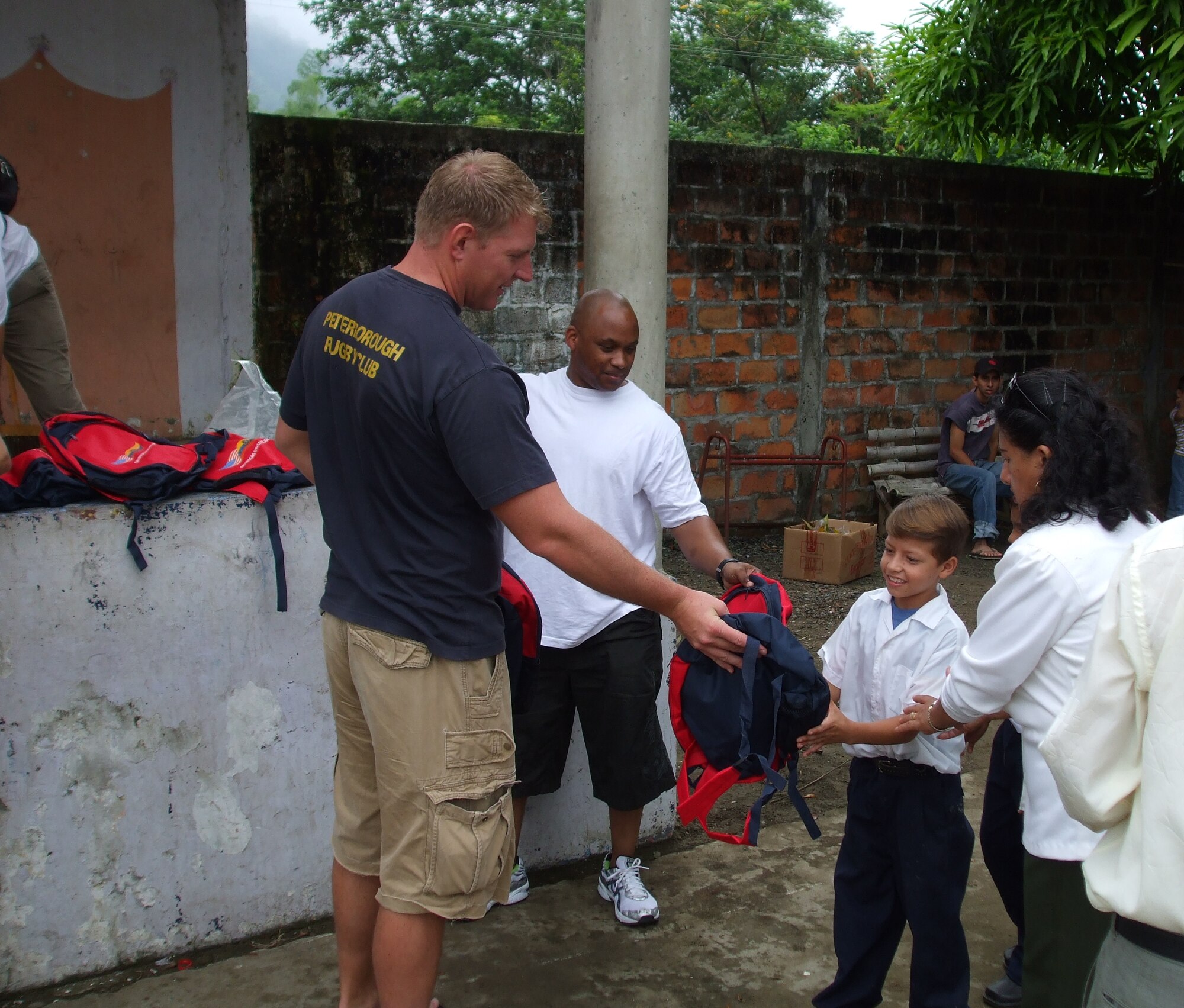 Technical Sergeants Alf Thompson (left) and Travis Dunson, both Quality Assurance Evaluators at FOL Manta, hand out backpacks to children at the school Escuela  Cuenca near the town of Portoviejo, Ecuador on Wednesday, May 7.  Last week members of FOL Manta helped give away 6,500 backpacks to underprivileged children.  (U.S. Air Force photo/Chaplain (Capt.) Steven Survance)