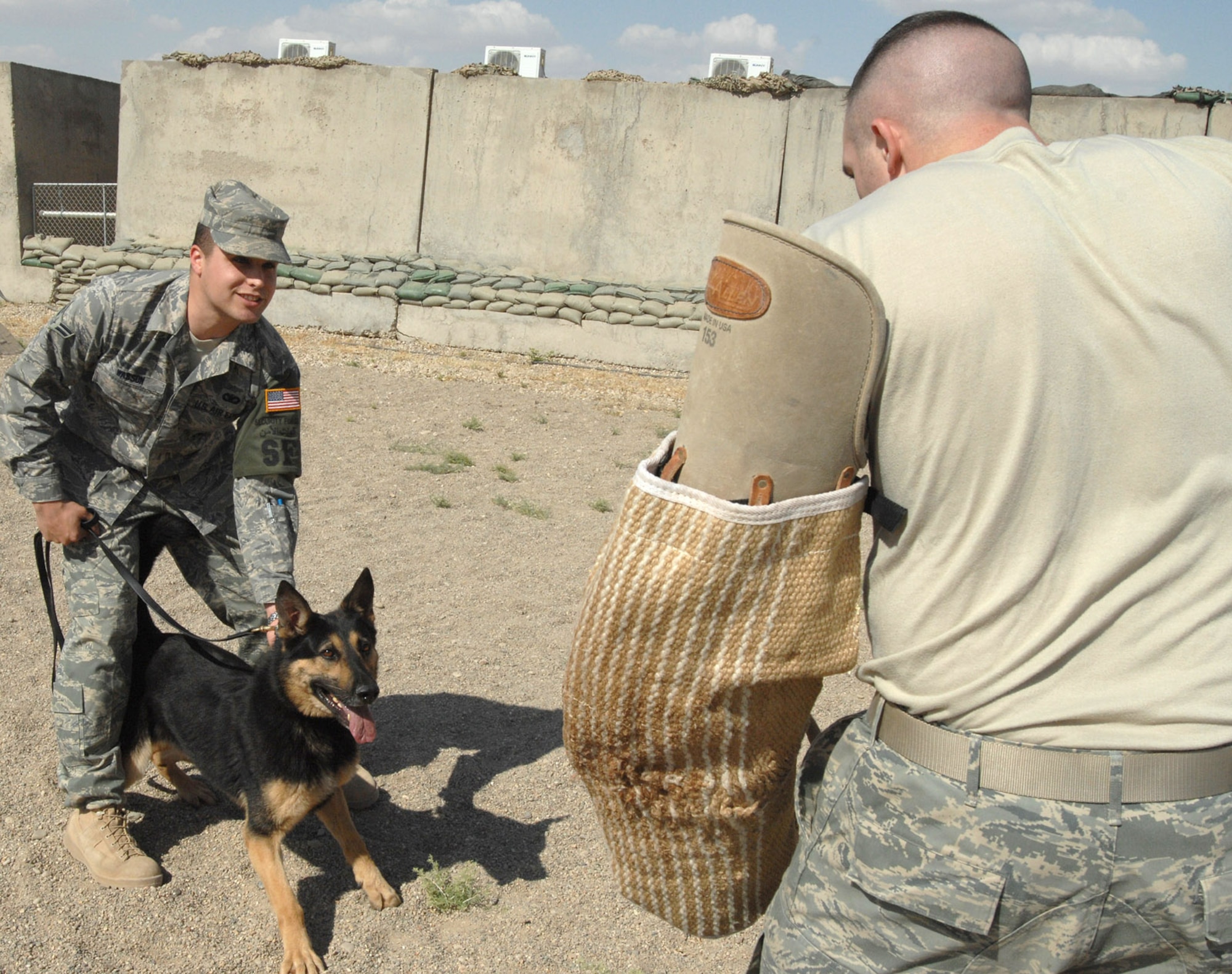 Airman 1st Class Ryan Wasson, 506th Expeditionary Security Forces Squadron military working dog handler, holds his dog "Charlie" back from attacking Staff Sgt. Kevin Nelson, 506th ESFS military working dog handler, during a recent training event here. Air Force dog handlers at Kirkuk are assigned to either the 506th Expeditionary Security Forces Squadron or 732nd Expeditionary Security Forces Squadron. Both squadrons have separate kennels and missions. (U.S. Air Force photo by Senior Airman Eric Schloeffel)