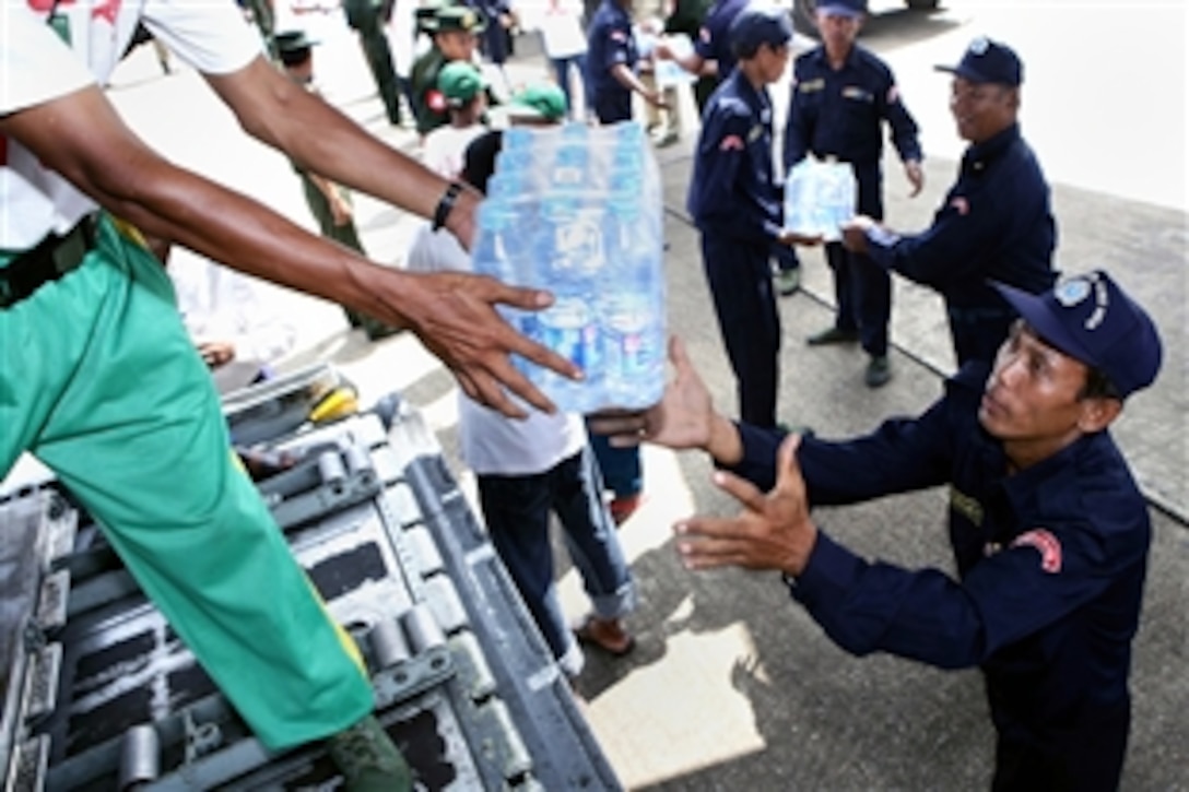 A Burmese civilian aid worker hands bottled water to a Burmese servicemember from a U.S. Air Force C-130 Hercules, May 12, 2008, Yangon International Airport, Burma. The plane carrying water, food and medical supplies provided relief to Burma, which was struck by Cyclone Nargis on May 2, 2008. 