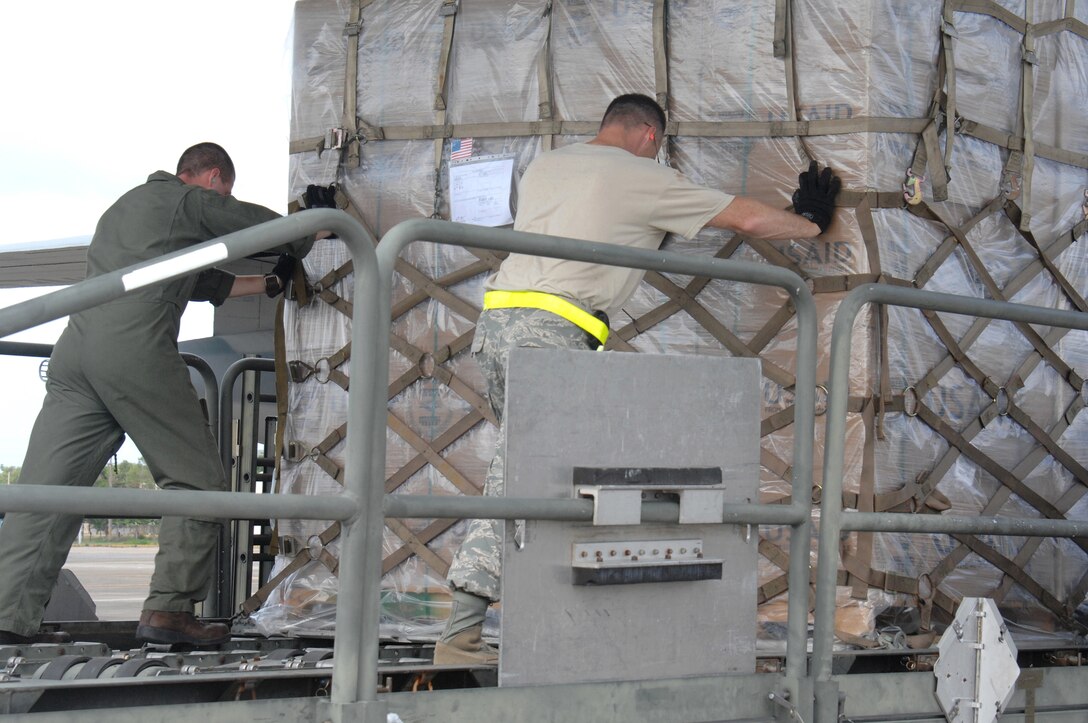 Technical Sgt Tracey Johnston and Sgt Tommy Coleman, push a cargo load onto a C-130 Hercules the morning of May 13 for delivery of crucial supplies to the people of Burma. TSgt Johnston is forward deployed from Andersen AFB, Guam with the 36th Contingency Response Group and Sgt Tommy Coleman is with the Marine Aerial Refueler Transport Squadron in Okinawa, Japan. (U.S. Air Force photo by Senior Airman Sonya Croston)
