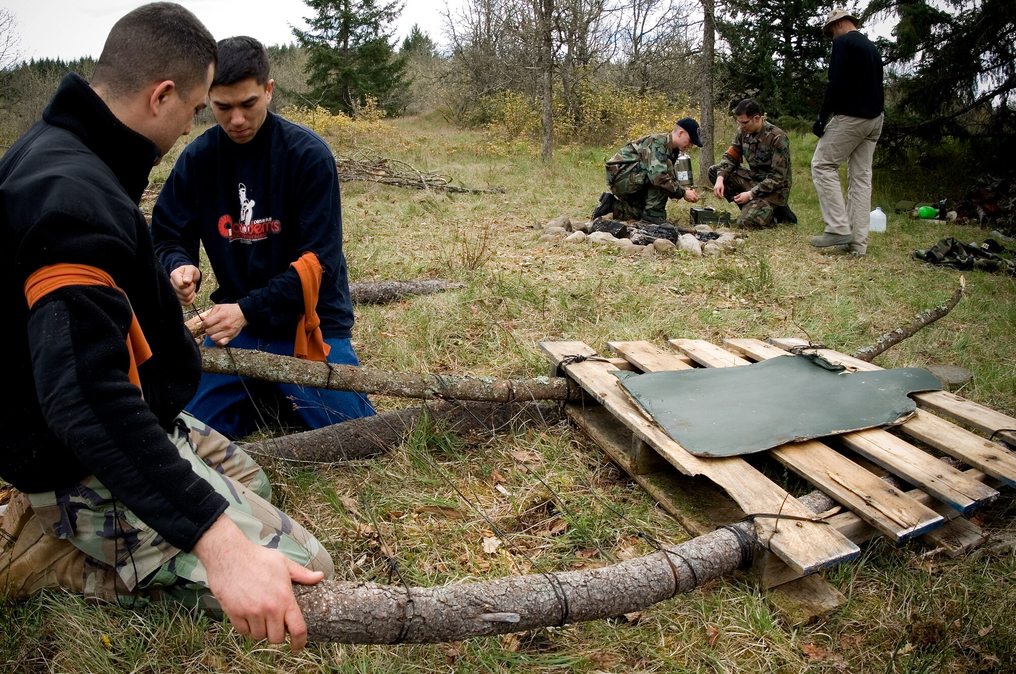 Staff Sgt. Timothy Padgett, 62nd Logistics Readiness Squadron, left, and Senior Airman Anthony Jenkins, 62nd Security Forces Squadron, build a makeshift litter in preparation for the competition’s final scenario while other team members gather tinder for an evening campfire.