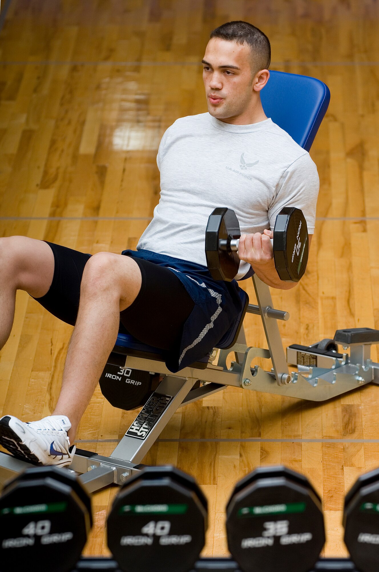 Senior Airman David Bauld, 446th Aircraft Maintenance Squadron, does some dumbbell curls during a recent workout at the Fitness Center Annex. (Photo by Abner Guzman.)