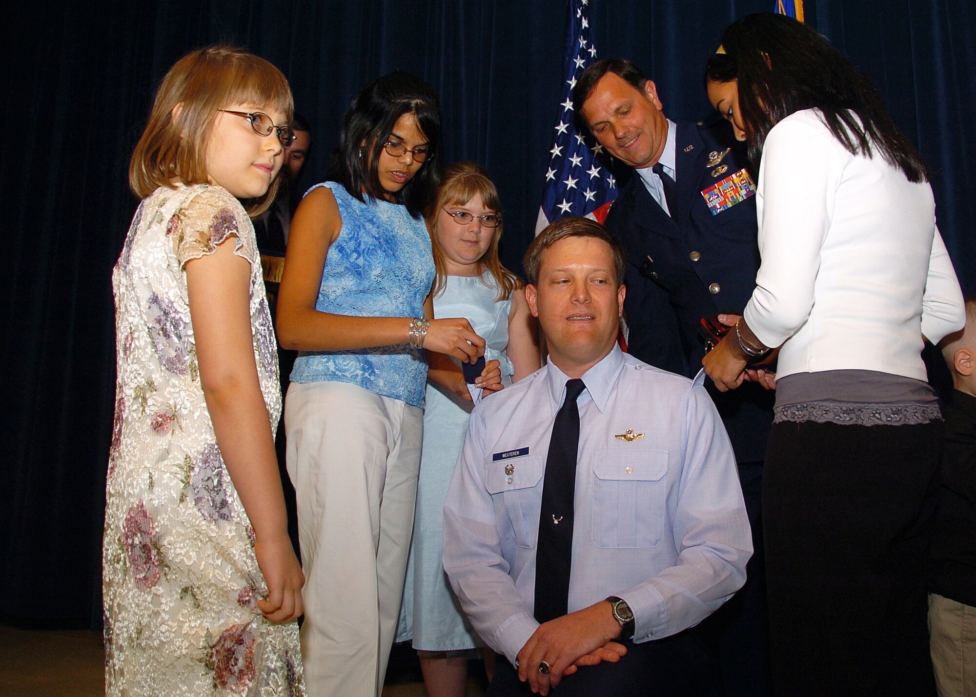 Col. (ret.)  Richard M. Zink looks on as the daughters of newly promoted Col. Evin R. Westeren, 97th Mission Support Group deputy commander, remove shoulder boards and replace them with the correct rank insignia. Colonel Westeren was promoted to his current rank in a ceremony officiated by Colonel Zink, April 30, at Altus Air Force Base, Okla.