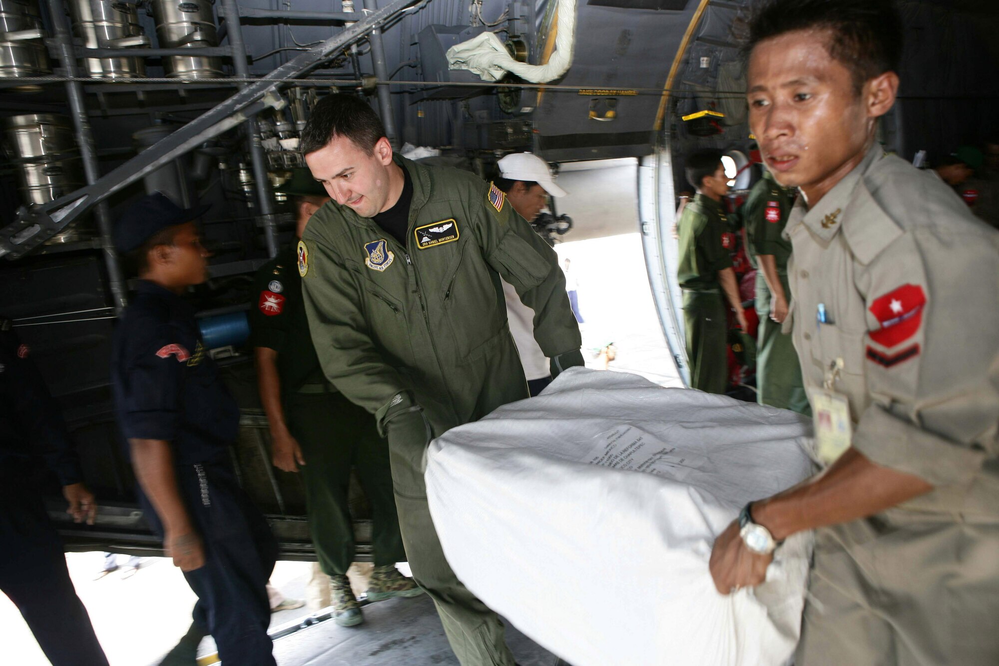 Burmese and U.S. servicemembers work together to unload supplies from a U.S. Air Force C-130 Hercules May 12 at Rangoon International Airport in Burma. The shipment of water, mosquito nets and blankets arrived on the first of three planned relief flights to provide aid to citizens devastated by Tropical Cyclone Nagris. (U.S. Marine photo/Sgt. Andres Alcaraz)