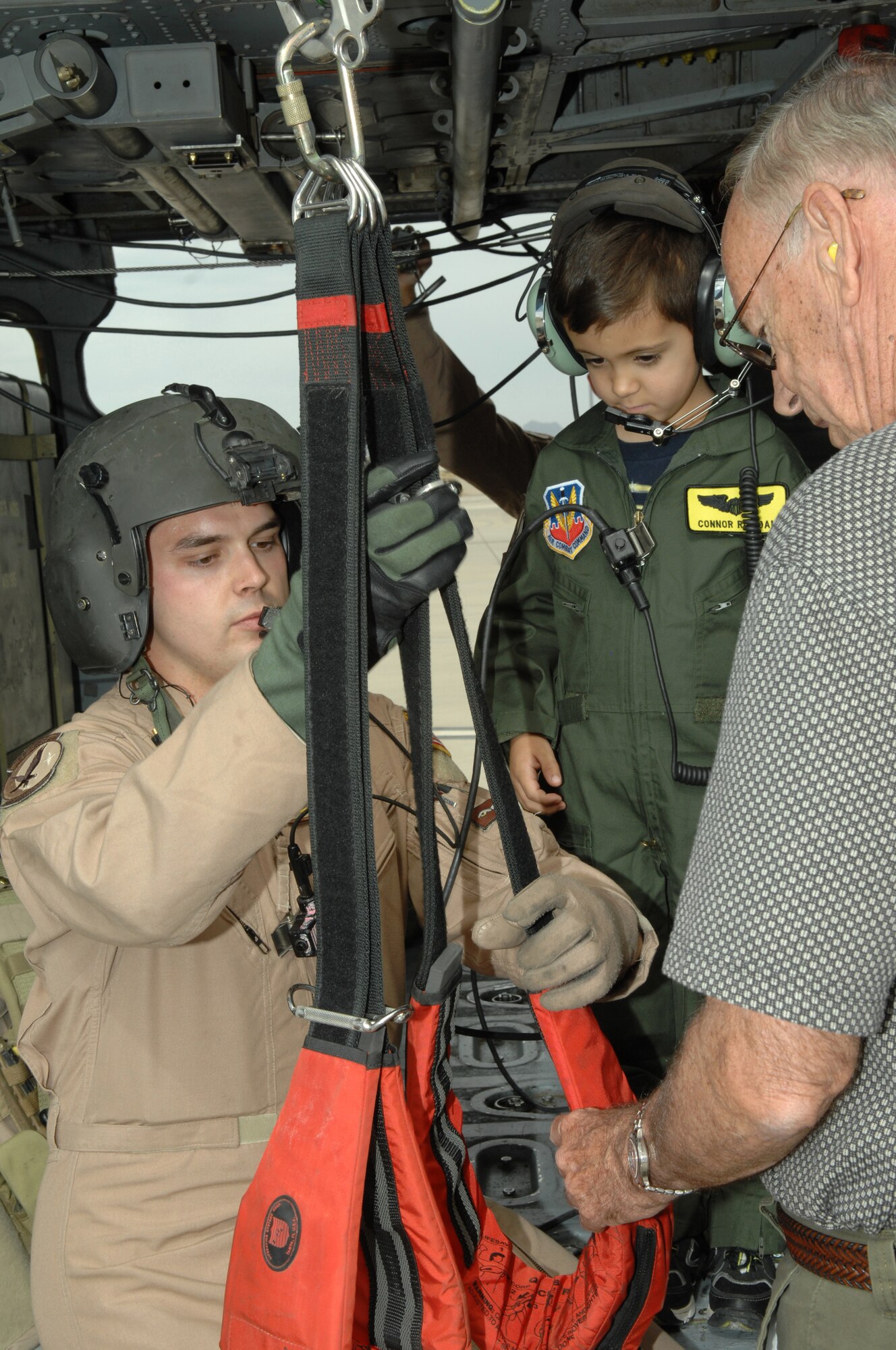 Staff Sgt. Francis Kunkel, 55th Rescue Squadron, helps Connor Riordan, age 5, into a harness on an HH-60 Pavehawk as Connor's Grandfather Neil Riordan watches, here, May 9.  Connor participated in the Pilot for a Day program designed to give local children with illnesses an enjoyable day completely devoted to them and their interest in aviation. (U.S. Air Force photo/Airman 1st Class Noah R. Johnson)