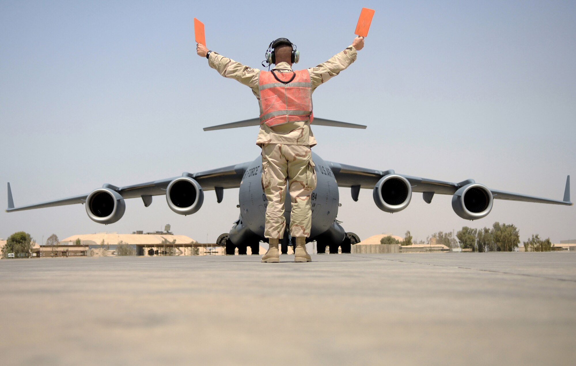 Tech. Sgt. Frank Wisnieski prepares to stop a C-17 Globemaster III May 12 at Balad Air Base, Iraq. Coordinating the safe arrivals and departures of dozens of aircraft daily is a 24-hour operation that is executed seamlessly by Airmen working in the transient alert shop. Sergeant Wisnieski is a 332nd Expeditionary Maintenance Squadron transient alert supervisor deployed from Ramstein Air Base, Germany. (U.S. Air Force photo/Senior Airman Julianne Showalter) 
