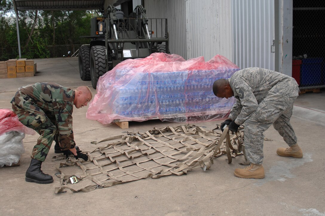 UTAPAO, Thailand - Staff Sgt. Shaun Kegin and Master Sgt. Don Gambles, both from the 36th Contingency Response Group, prepare to place cargo netting over a pallet of bottled water for the first drop of supplies making its way into Burma after the May 2 destruction from Cyclone Nargis. (USAF Photo/Senior Airman Sonya Croston)