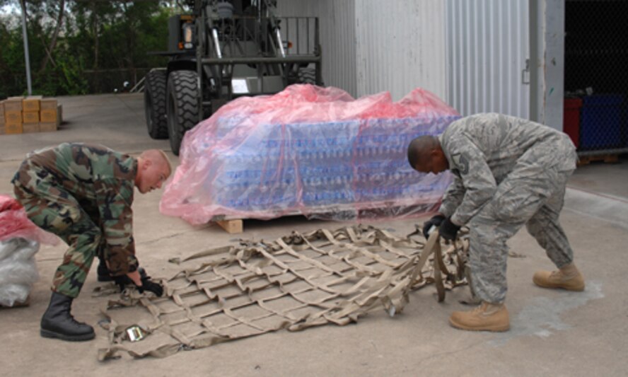 UTAPAO, Thailand - Staff Sgt. Shaun Kegin and Master Sgt. Don Gambles, both from the 36th Contingency Response Group, prepare to place cargo netting over a pallet of bottled water for the first drop of supplies making its way into Burma after the May 2 destruction from Cyclone Nargis. (USAF Photo/Senior Airman Sonya Croston)