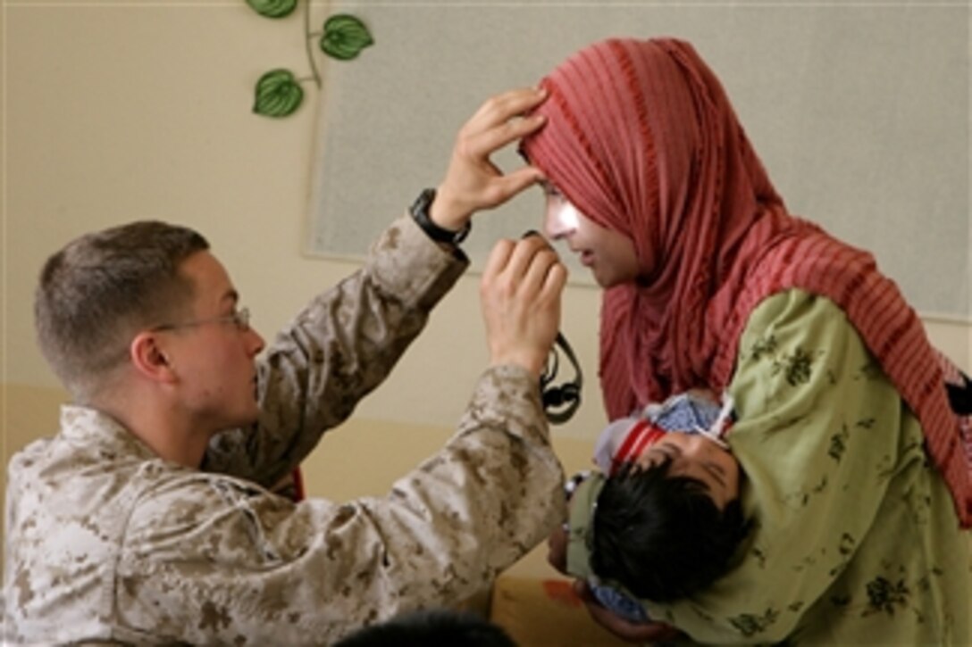 Navy Lt. Robert F. Render (left), Battalion Surgeon, 1st Battalion, 9th Marines, examines a woman's eyes at the Al Jazeera Elementary School in Northern Ramadi, Iraq, on May 6, 2008.  Marines and sailors are at the school to pass out food and provide medical treatment to students and adults.  