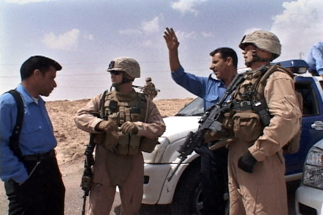 Iraqi Police inform Sgt. Dennis K. Derr II (right) and 1st Lt. Luke R. Barnes, patrol leaders of Section A, Mobile Assault Platoon, Weapons Company, 3rd Battalion, 6th Marine Regiment, Regimental Combat Team-1, of a possible improvised explosive device on the roadway outside of Ferris Town May 13. (Official U.S. Marine Corps photo by Cpl. Chris Lyttle) (RELEASED)::r::::n:: ::r::::n::