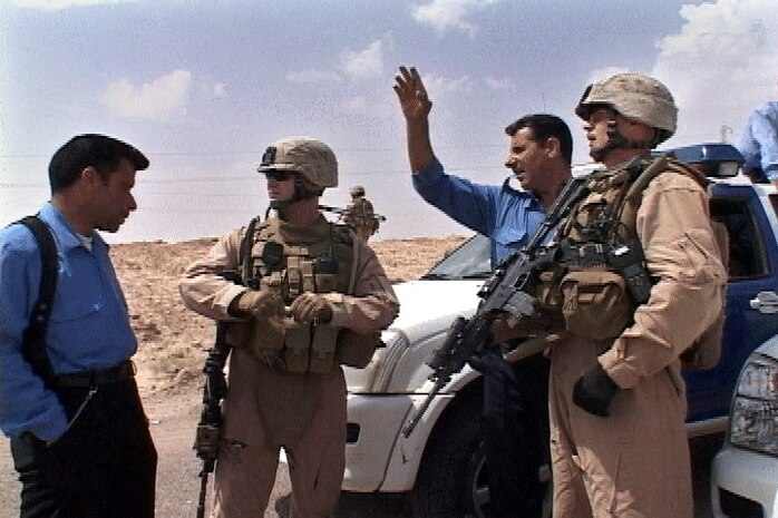 Iraqi Police inform Sgt. Dennis K. Derr II (right) and 1st Lt. Luke R. Barnes, patrol leaders of Section A, Mobile Assault Platoon, Weapons Company, 3rd Battalion, 6th Marine Regiment, Regimental Combat Team-1, of a possible improvised explosive device on the roadway outside of Ferris Town May 13. (Official U.S. Marine Corps photo by Cpl. Chris Lyttle) (RELEASED)::r::::n:: ::r::::n::