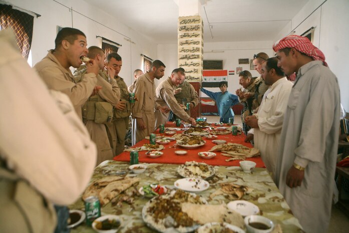 Enjoying plates of Iraqi cuisine, Marines with 2nd Platoon, 2nd Light Armored Reconnaissance Battalion, Regimental Combat Team 5 and an Iraqi family eat together during a feast the platoon was invited to attend in Al Anbar province, Iraq, May 13. During the feast, the men and the children gathered with the Marines to enjoy some rice, bread and a variety of meats and vegetables. The Iraqis were sharing their culture with 2nd Platoon, which is considered a high honor in their society.