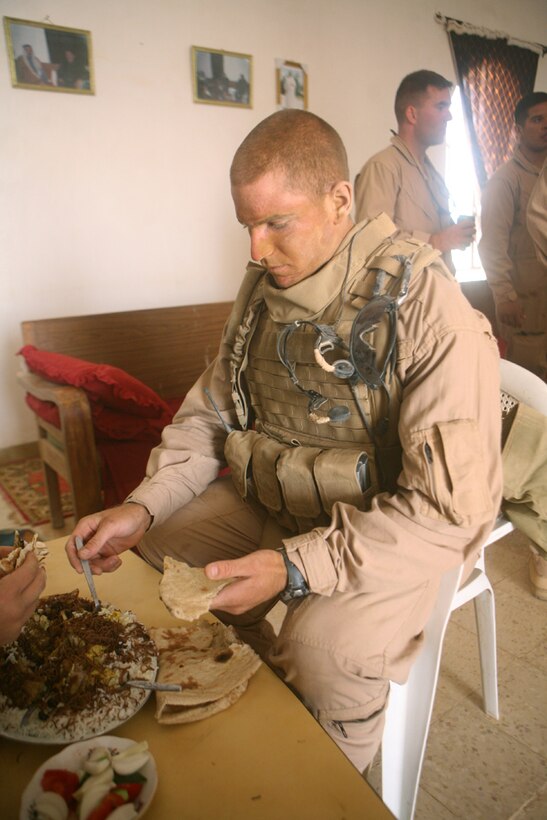 Cpl. John L. Jenness, a scout team leader with 2nd Platoon, Charlie Company, 2nd Light Armored Reconnaissance Battalion, Regimental Combat Team 5, enjoys a plate of Iraqi food during a feast bringing two cultures together in western Al Anbar province, Iraq, May 13. Second Platoon was conducting area patrols between the cities of Rutbah and Akashat, marking where each house was and conversing with the citizens of the households. The Marines were conducting a normal dayâ??s mission and were invited unexpectedly to dinner by a generous family.
