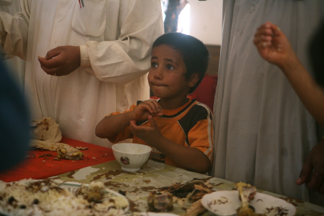 A small Iraqi boy watches as the adults and the Marines of 2nd Platoon, Charlie Company, 2nd Light Armored Reconnaissance Battalion, Regimental Combat Team 5 converse during a feast held for the platoon by an Iraqi family household western Al Anbar province, Iraq, May 13.  During the feast, the men and the children gathered with the Marines to enjoy some rice, bread and a variety of meats and vegetables. The Iraqis were sharing their culture with 2nd Platoon, which is considered a high honor in their society.