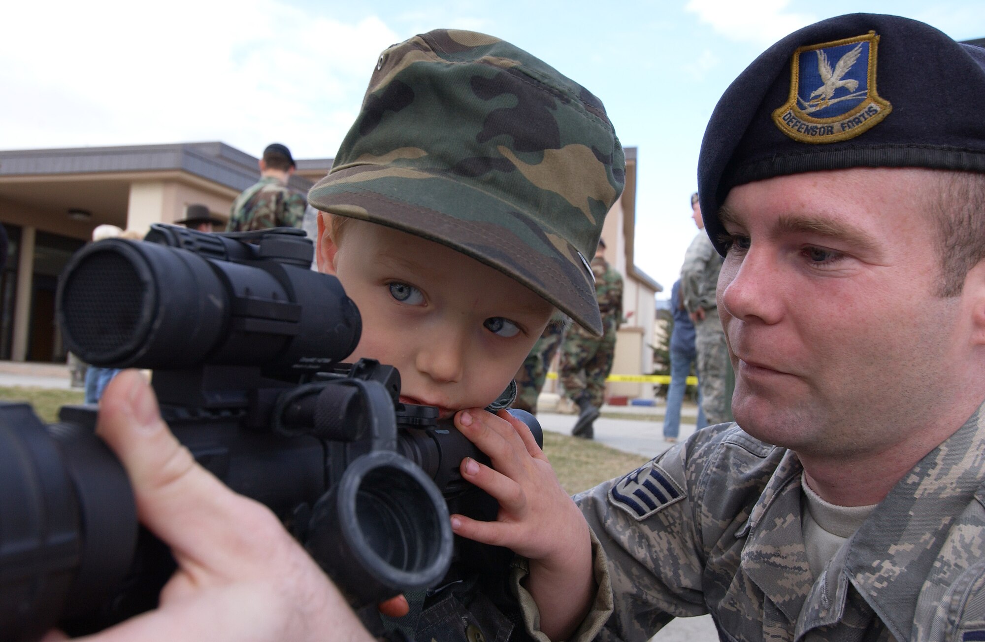 Bradley Summers peers down a laser dot scope on an M-4 Carbine while his father, Staff Sgt. Jerry Summers, helps hold the weapon up for him May 13, 2008, at Eielson Air Force Base, Alaska. The 354th Security Forces Squadron hosted events all throughout the week for families and community involvement with displays, demonstrations and games. Police week is designed to honor who are serving and who have served in law enforcement. Staff Sgt. Jerry Summers is assigned to the 354th SFS. (U.S. Air Force Photo/Airman 1st Class Jonathan Snyder)