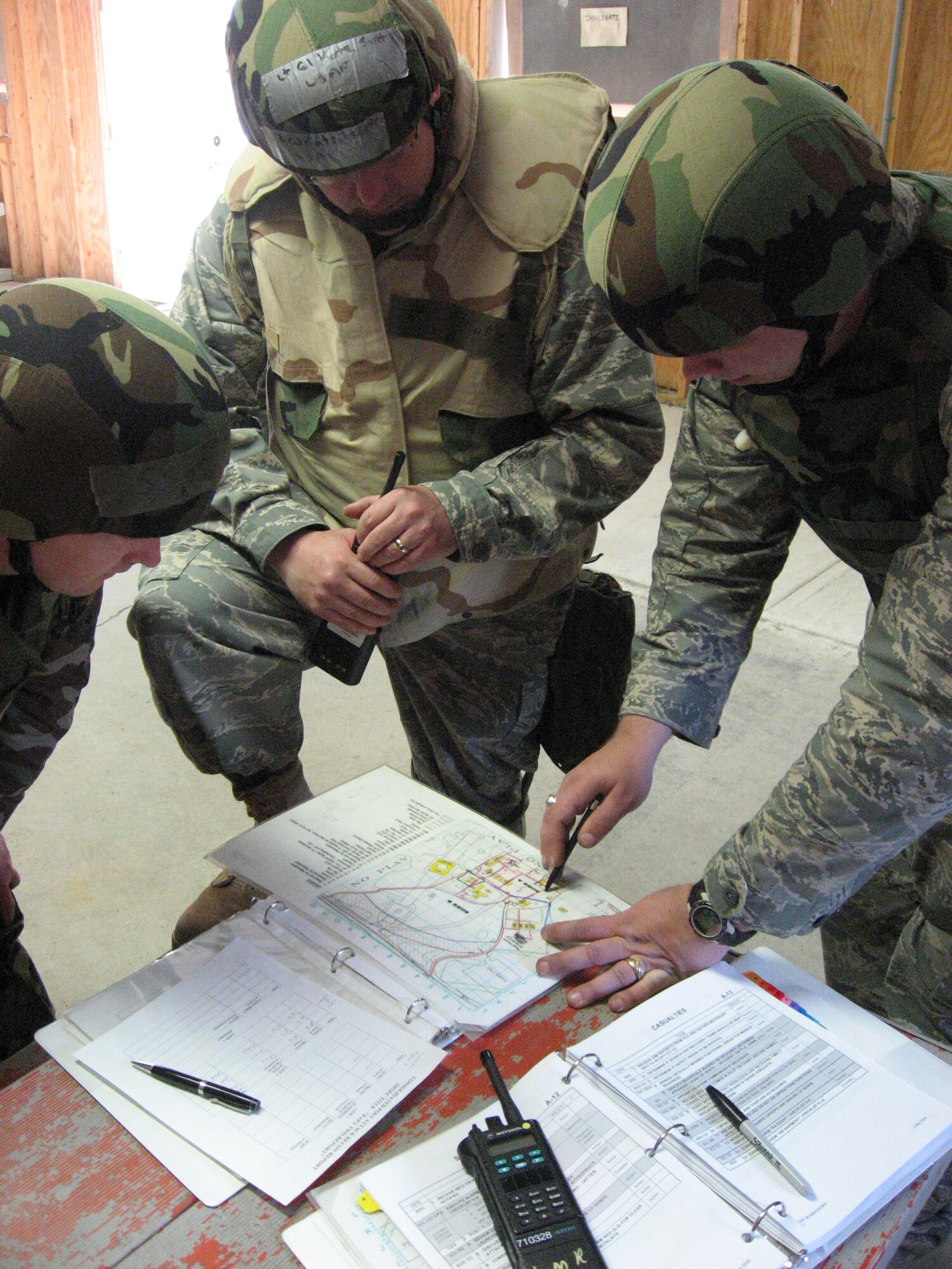 Staff Sgt. Michael Miller (right), Lt. Col. Scott Katz and Staff Sgt. Justin Ames identify damaged facilities on a map simulating their forward deployed location. Airmen from organizations across Wright-Patterson Air Force Base participated in an exercise May 13 which tested response to conventional and chemical attacks. Katz and Miller are with the 88th Mission Support Group.  Ames is a defender with the 88th Security Forces Squadron.  (U.S. Air Force photo/Derek Kaufman) 