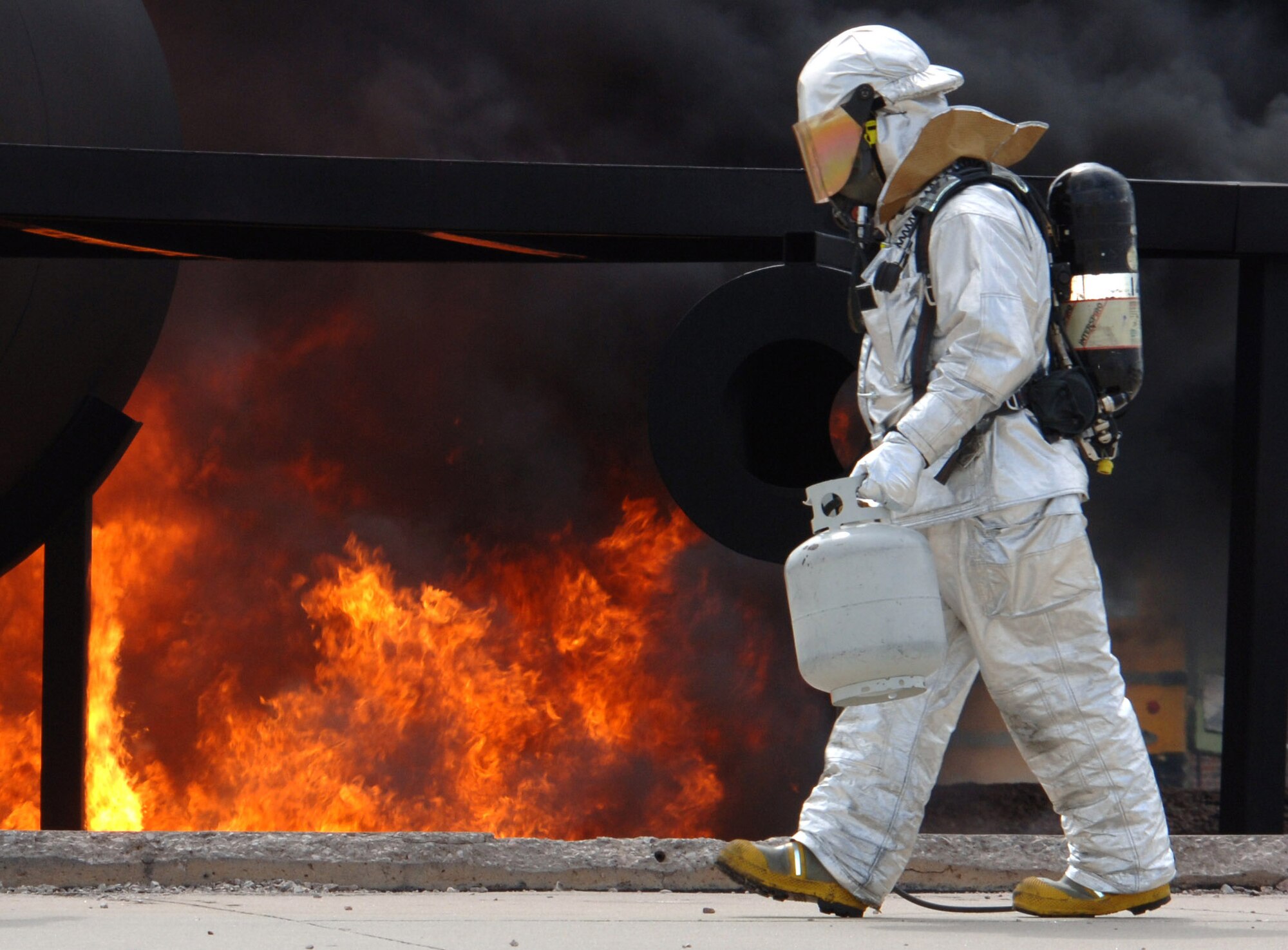 Staff Sgt. Chris Voth, 114th Air National Guard Civil Engineer Squadron fire fighter crew chief, carries a propane lighter used to ignite a training fire at Ellsworth May 13.  Pit fires are lit regularly to improve training and readiness; this training event involved Ellsworth Airmen as well as South Dakota Air National Guard members. (U.S. Air Force photo/Airman Corey Hook)
